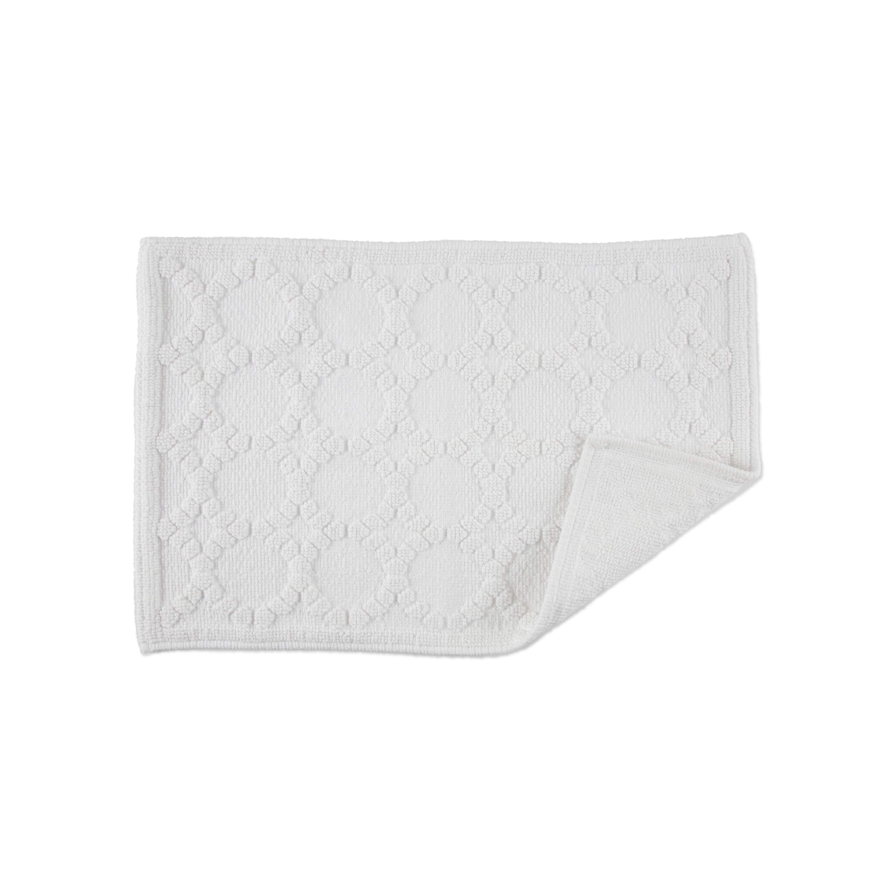 White bath rug with a textured geometric pattern and a folded corner.