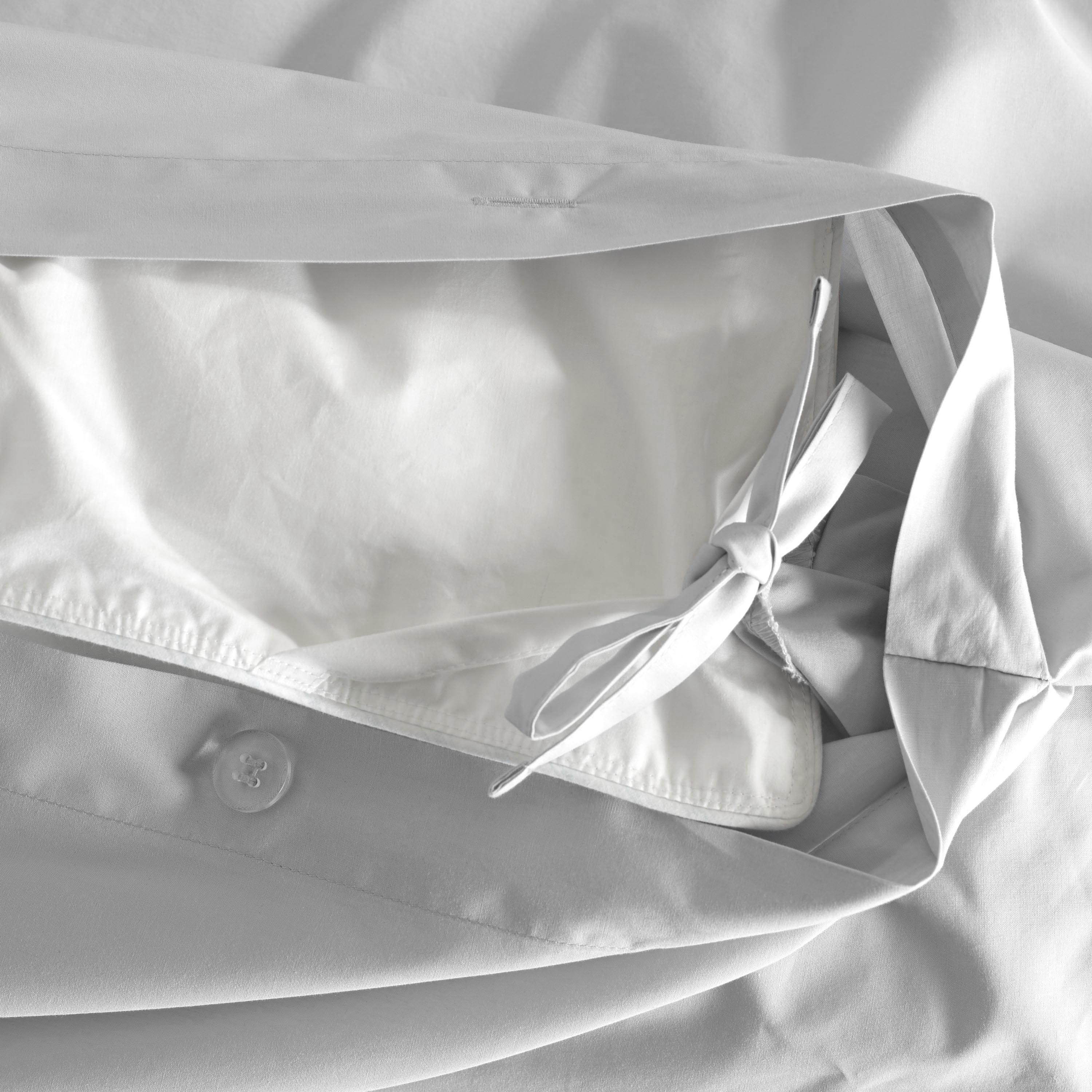 Close-up of a light gray duvet cover showing a tie closure and button detail.