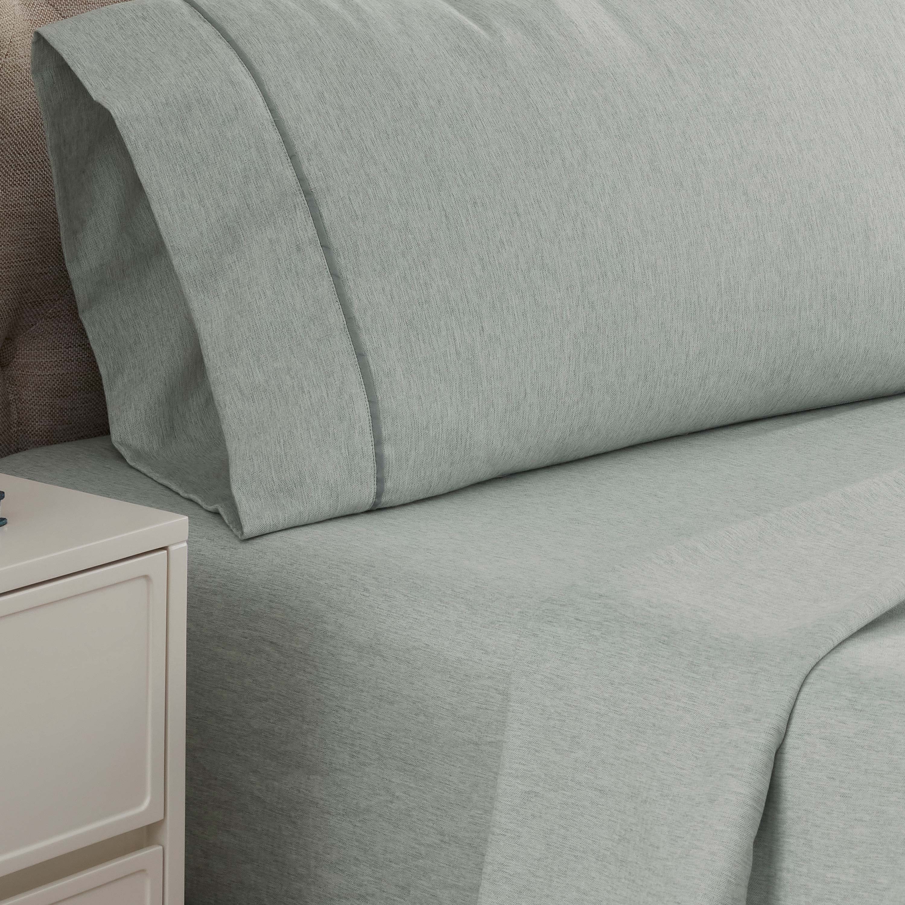 Light green herringbone-patterned sheet set with matching pillowcases on a bed.
