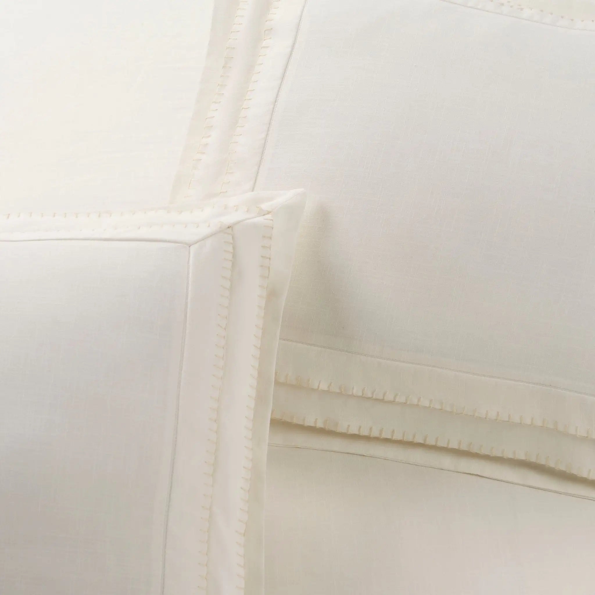 Close-up of an ivory pillow sham with decorative stitched border detailing.