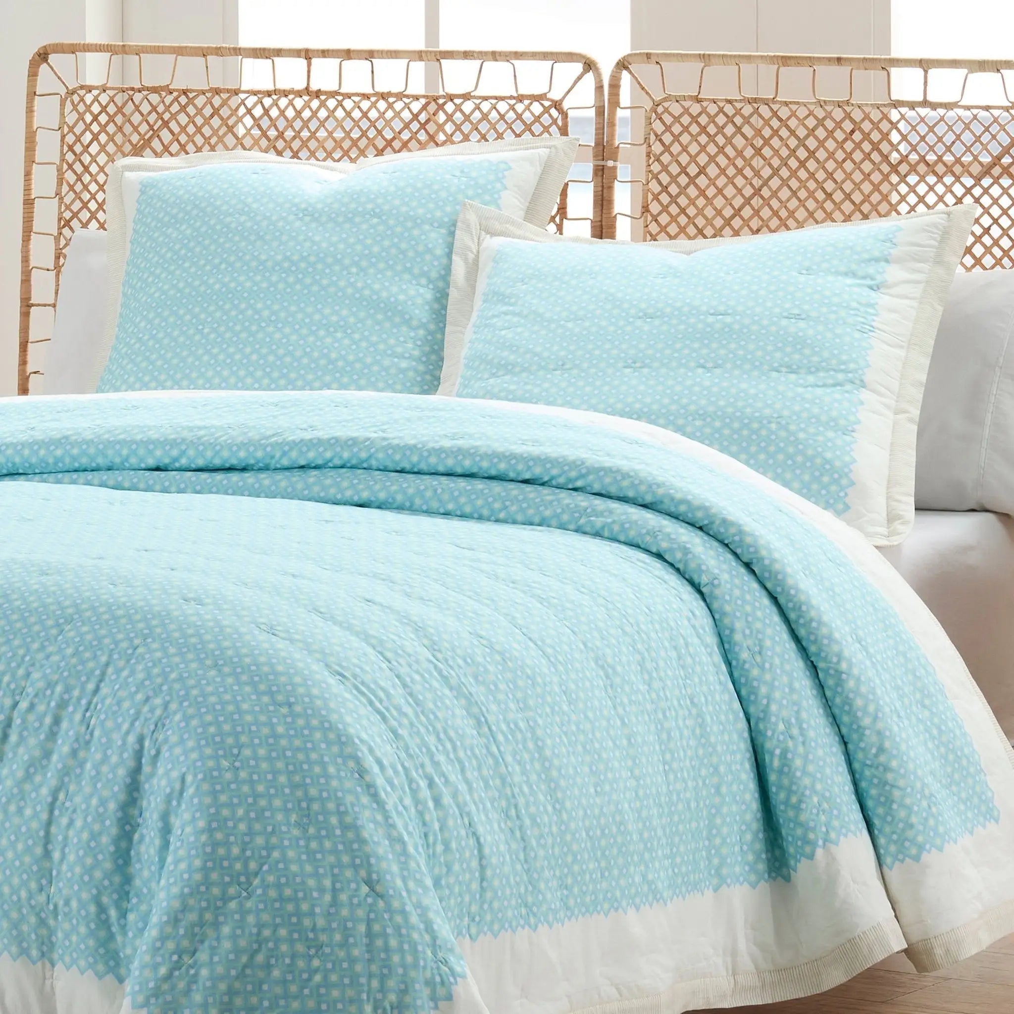 Light blue quilt and euro set on a bed.