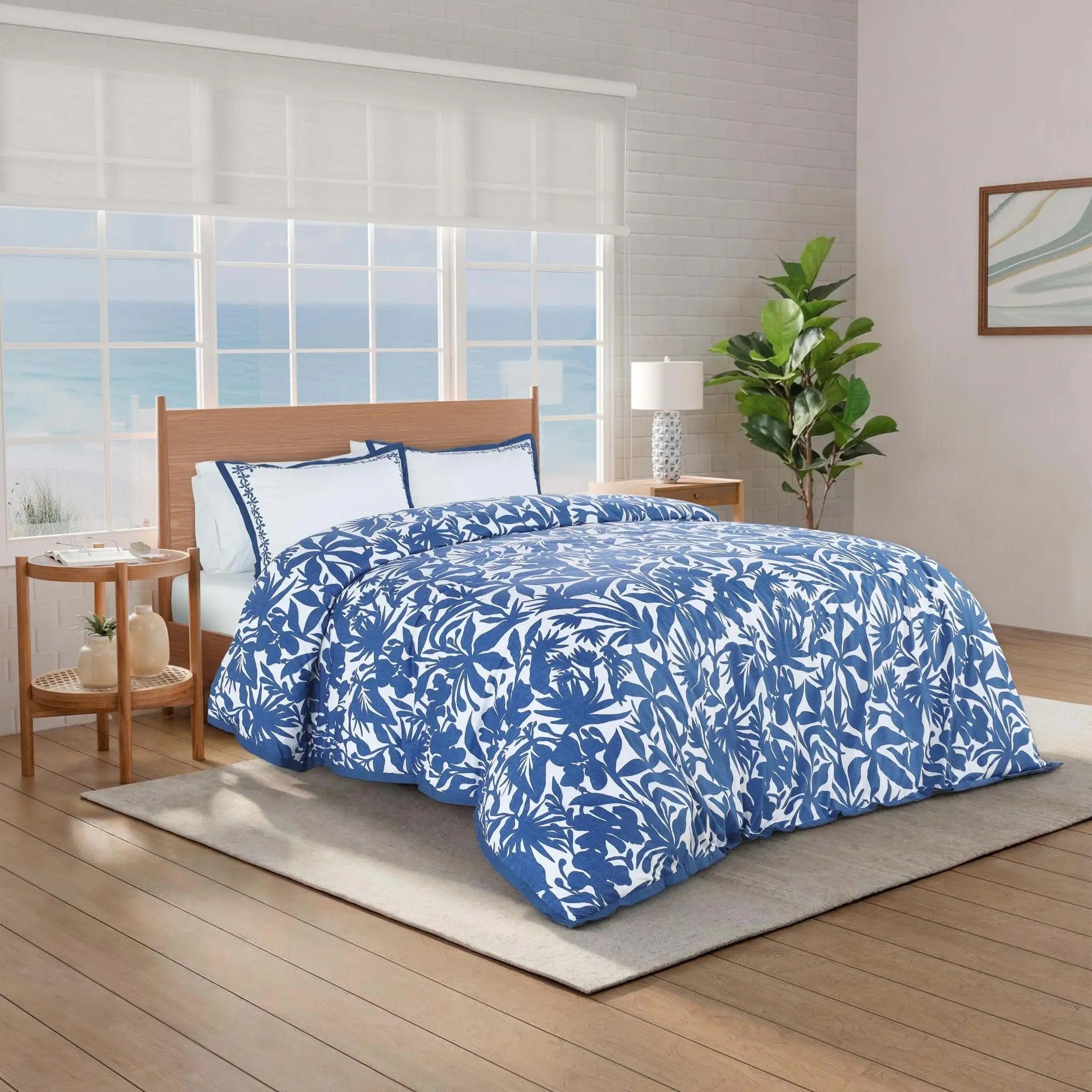 A bed dressed in a blue and white tropical floral print comforter set.