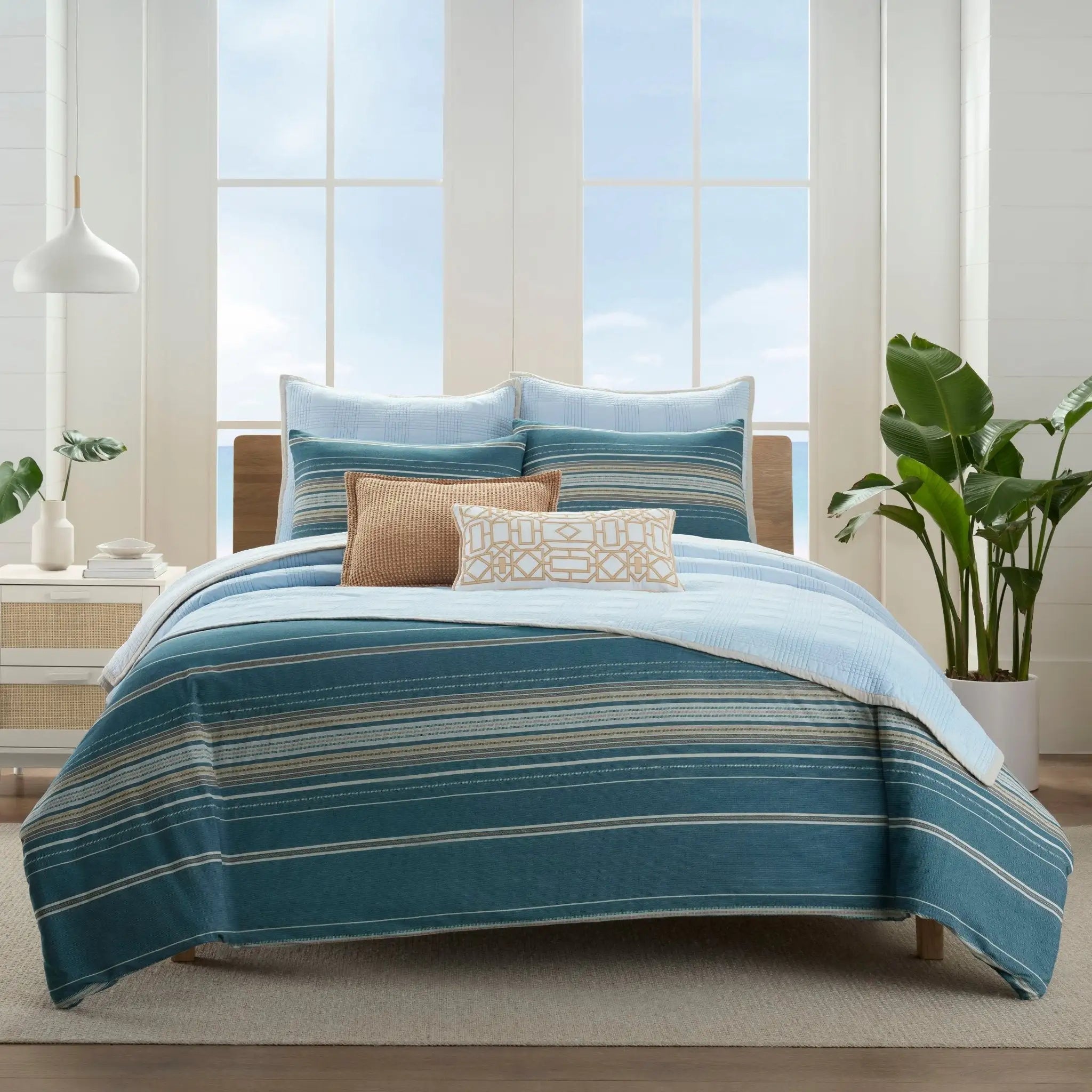 Striped comforter set on a bed in a bright room.