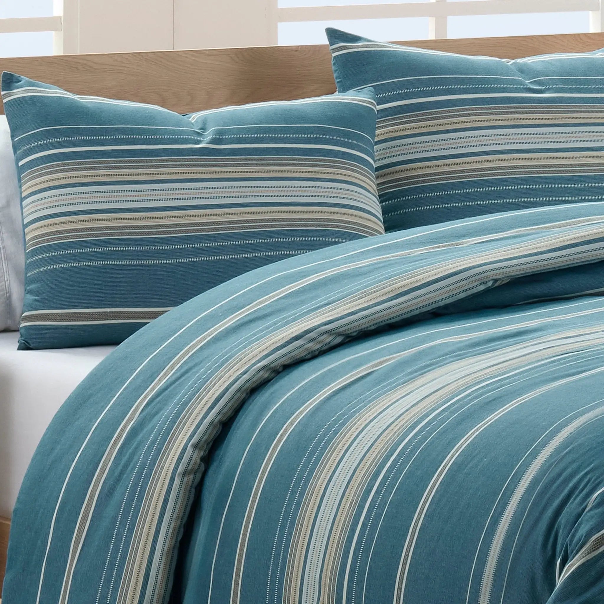 Striped blue and gray comforter set on a bed with pillow shams.