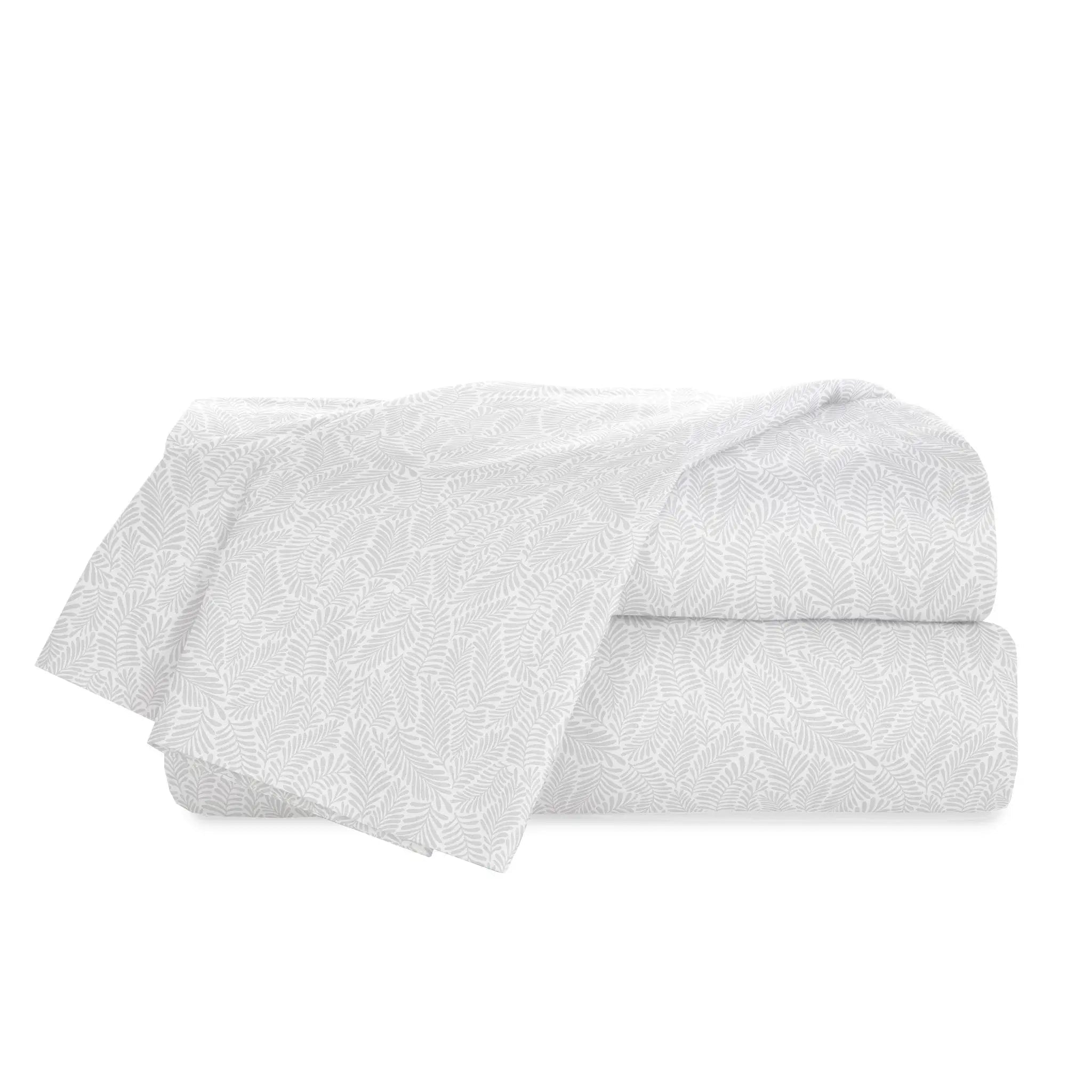 A folded white bedding set, likely a sheet set, featuring a delicate, tonal leaf or fern-like jacquard pattern, presented on a solid white background.