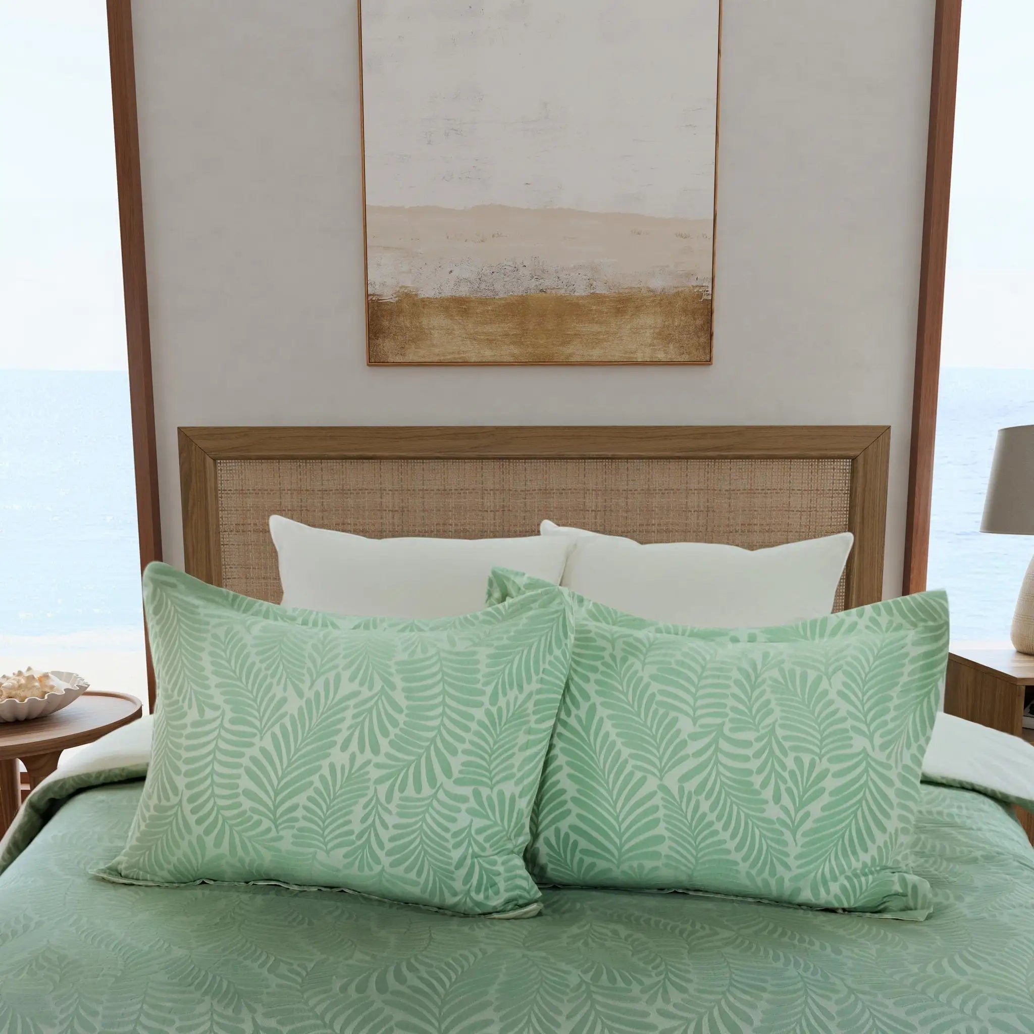 A bed dressed in a light green patterned bedding set with two matching pillow shams, styled in a bright bedroom.