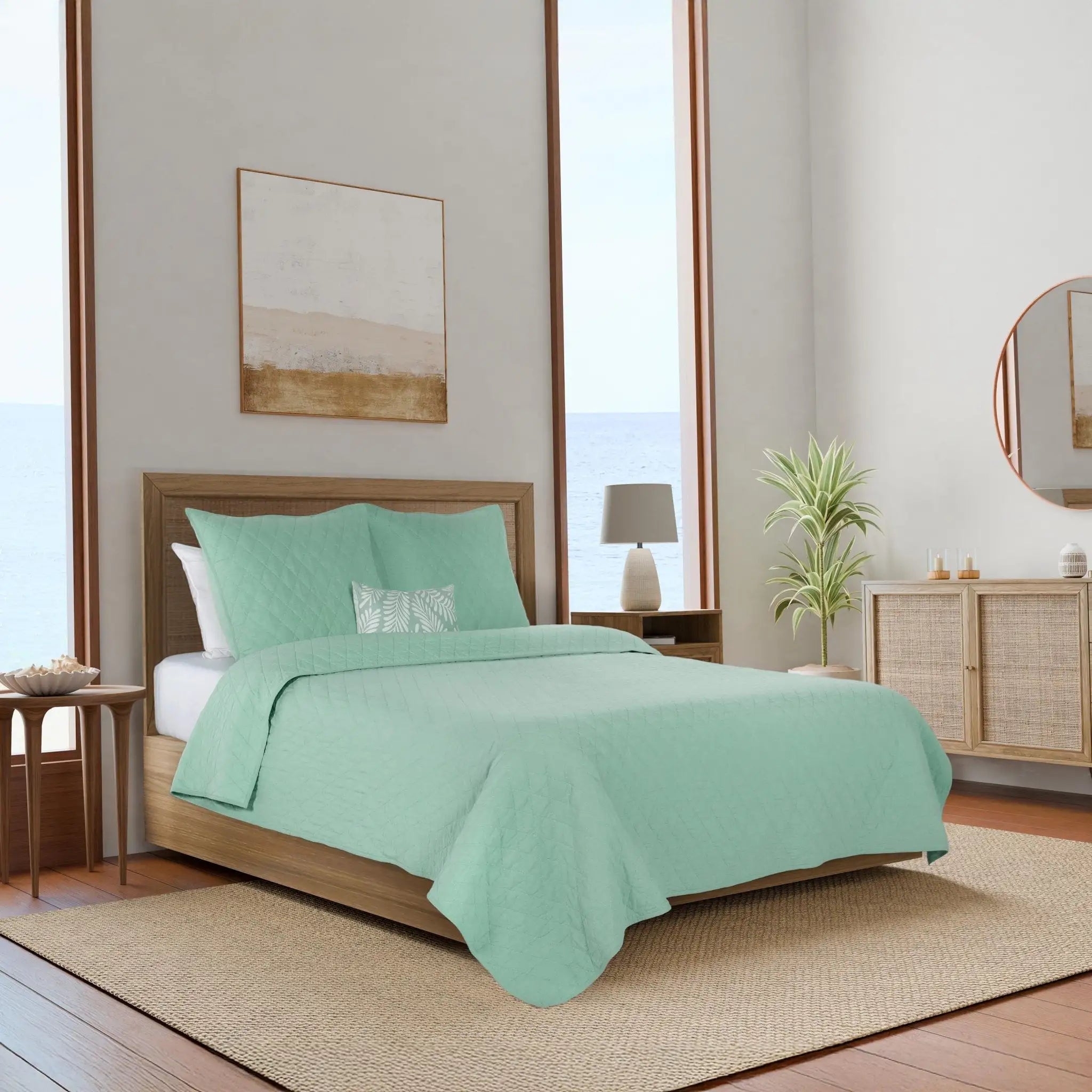 A bed dressed in a mint green quilt and matching euros.