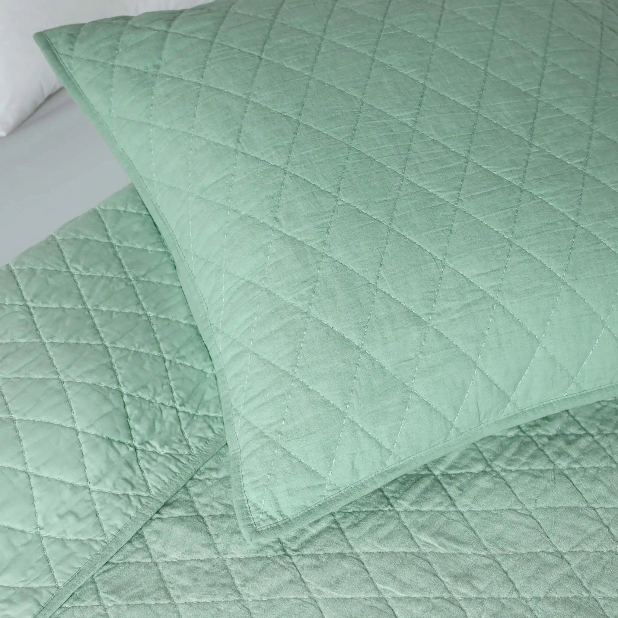 Quilted green fabric with diamond pattern on a white background