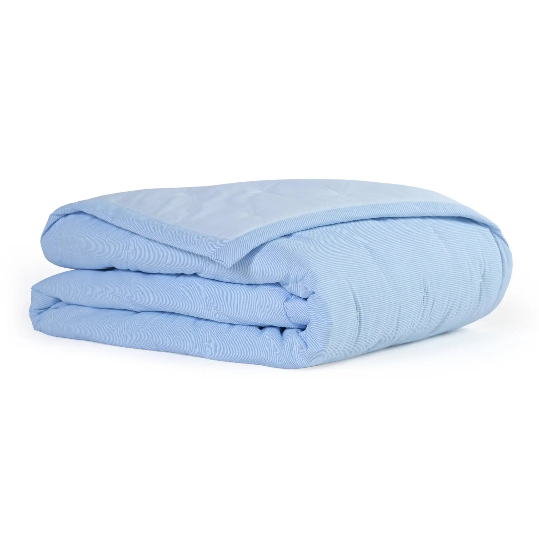 Folded light blue quilt on a white background
