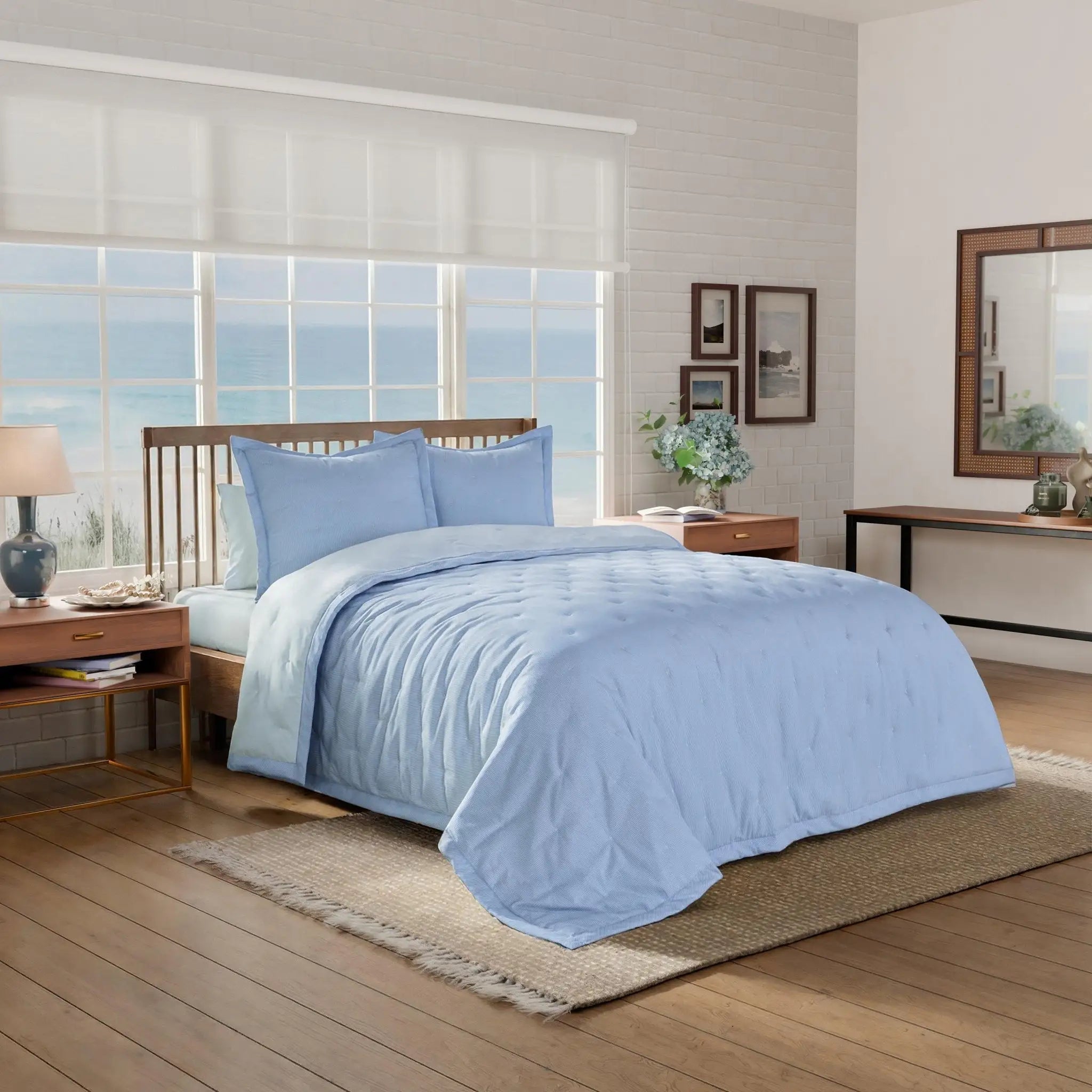 Bedroom with light blue quilt and euros on a bed.