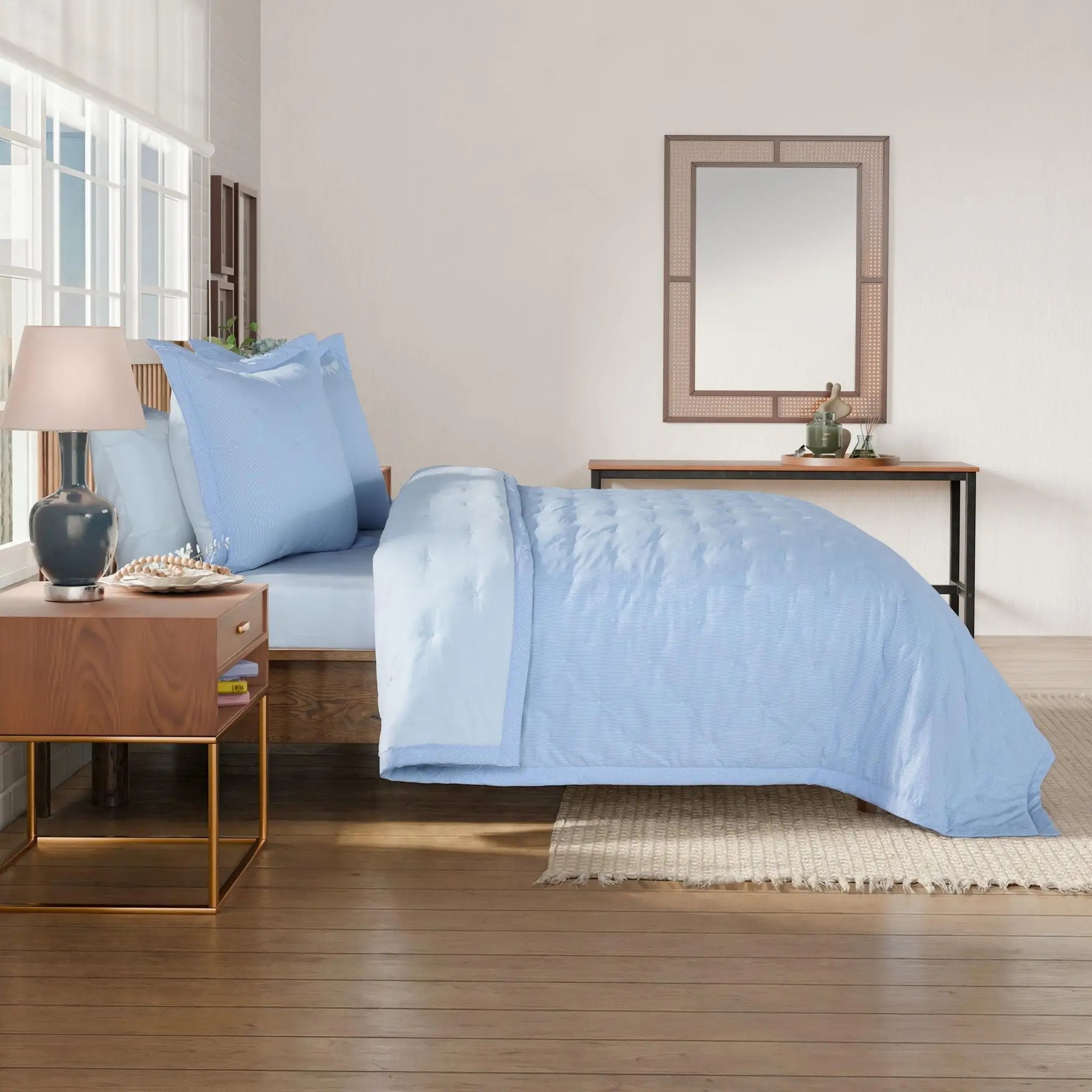Bedroom with a bed covered in blue quilt and 2 euros.