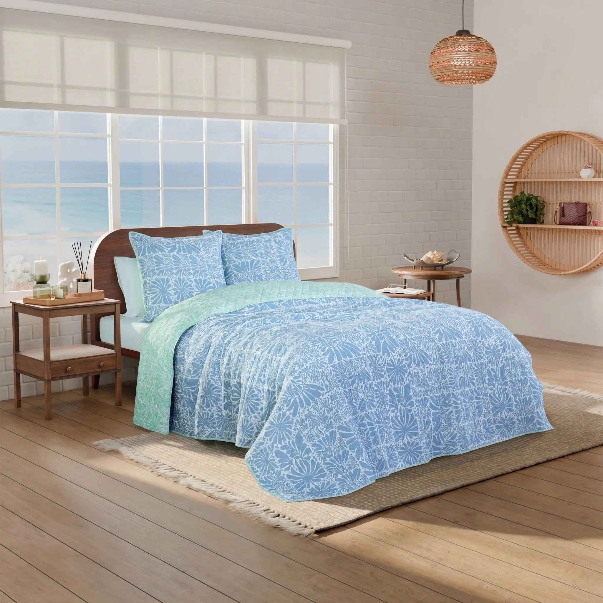 Bed with blue and green floral-patterned quilt in a room.
