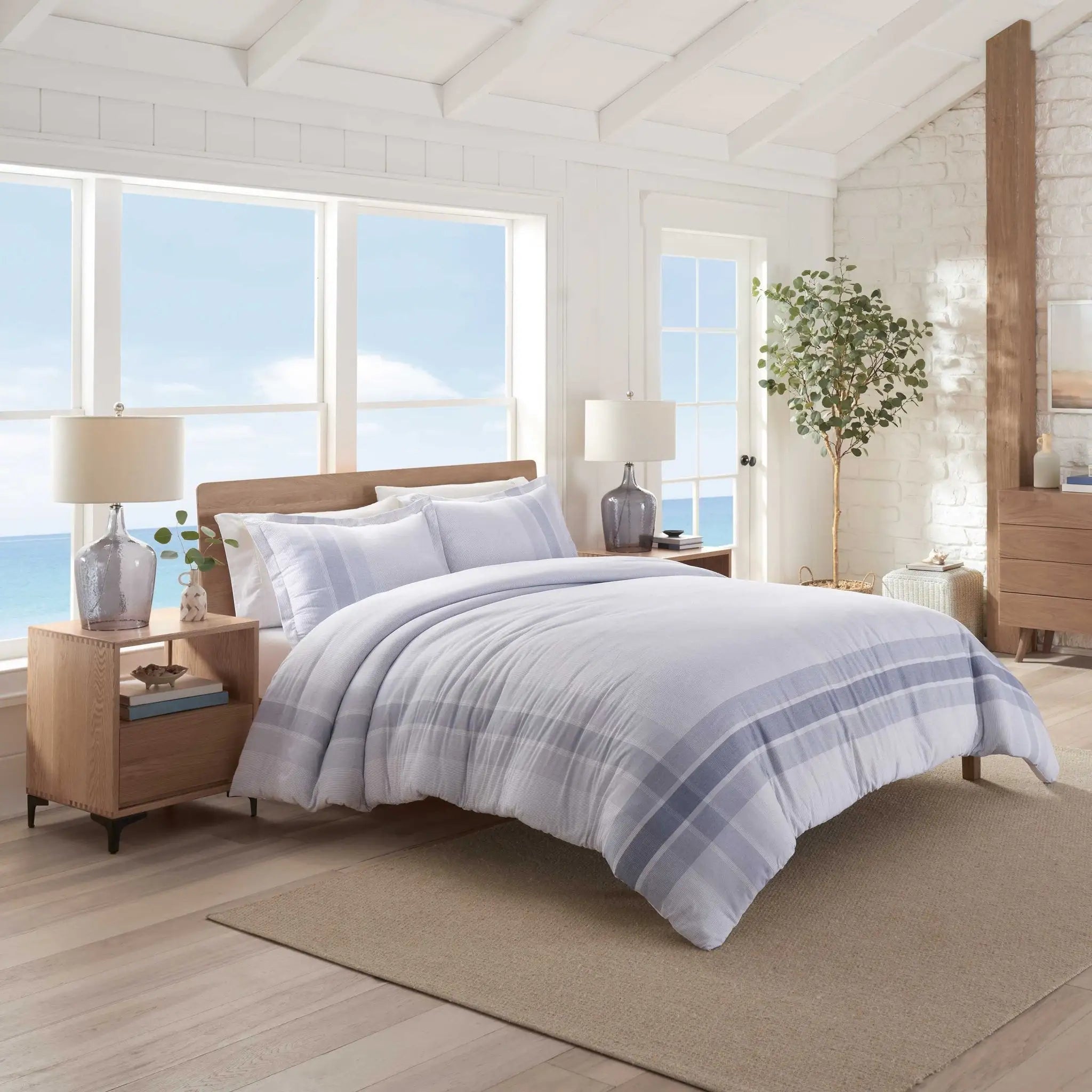 Bedroom with a neatly made bed featuring a plaid comforter and two pillow shams.