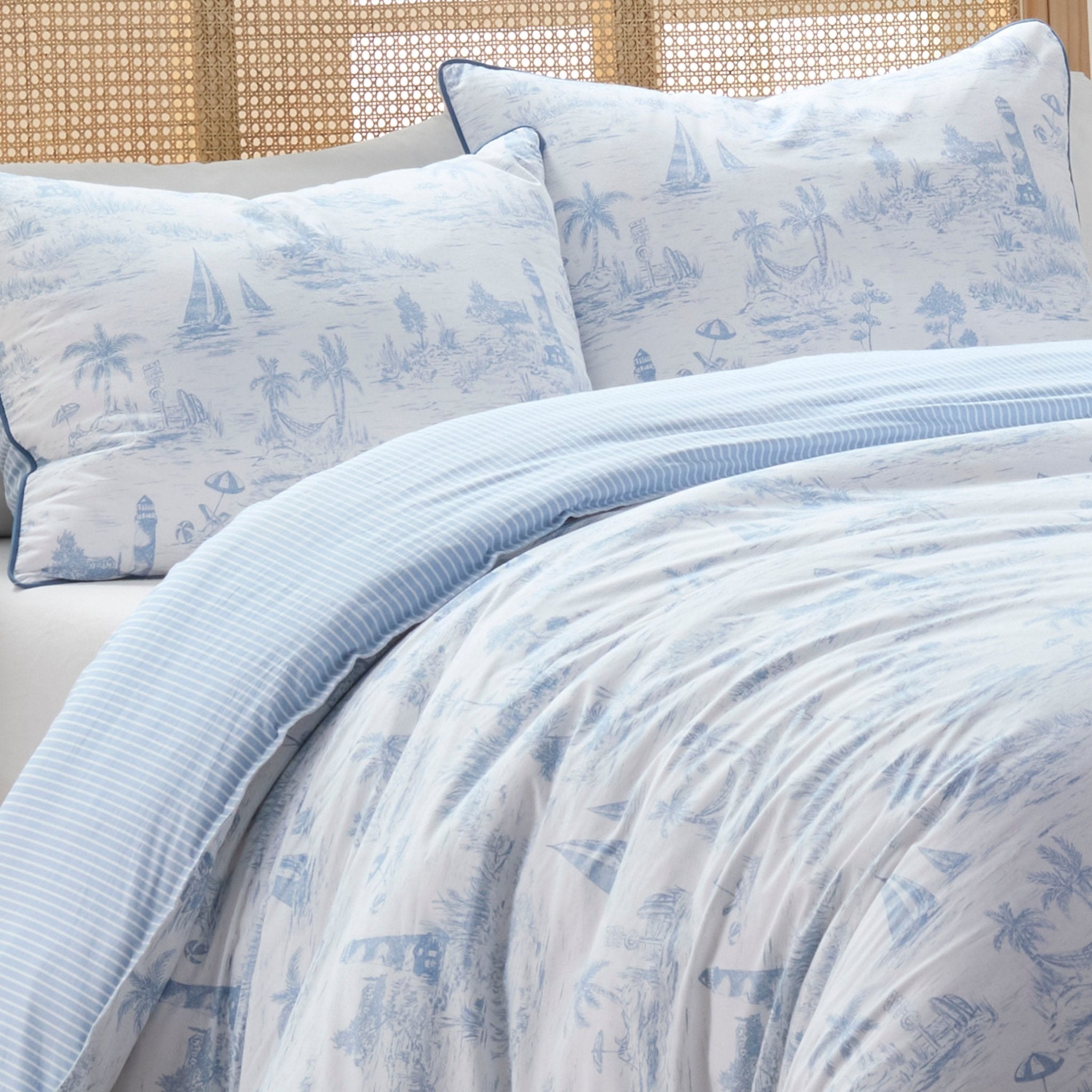 Blue and white patterned bedding set on a bed with a woven headboard.