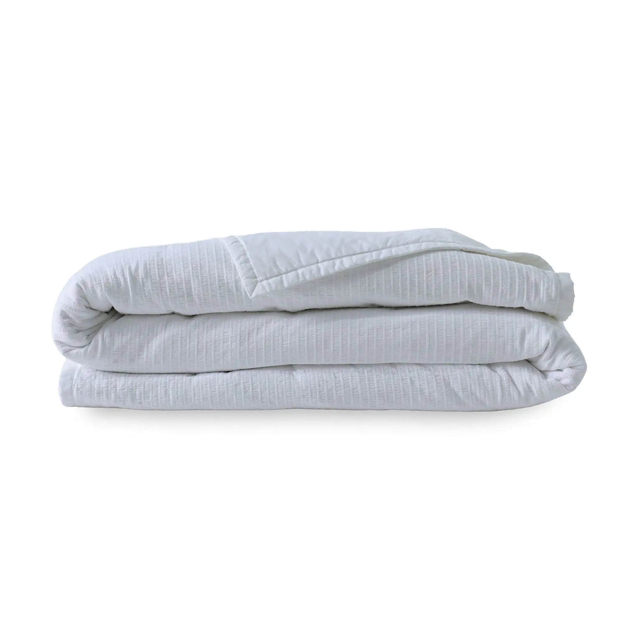 A folded white textured quilt, shown on a clean white background.