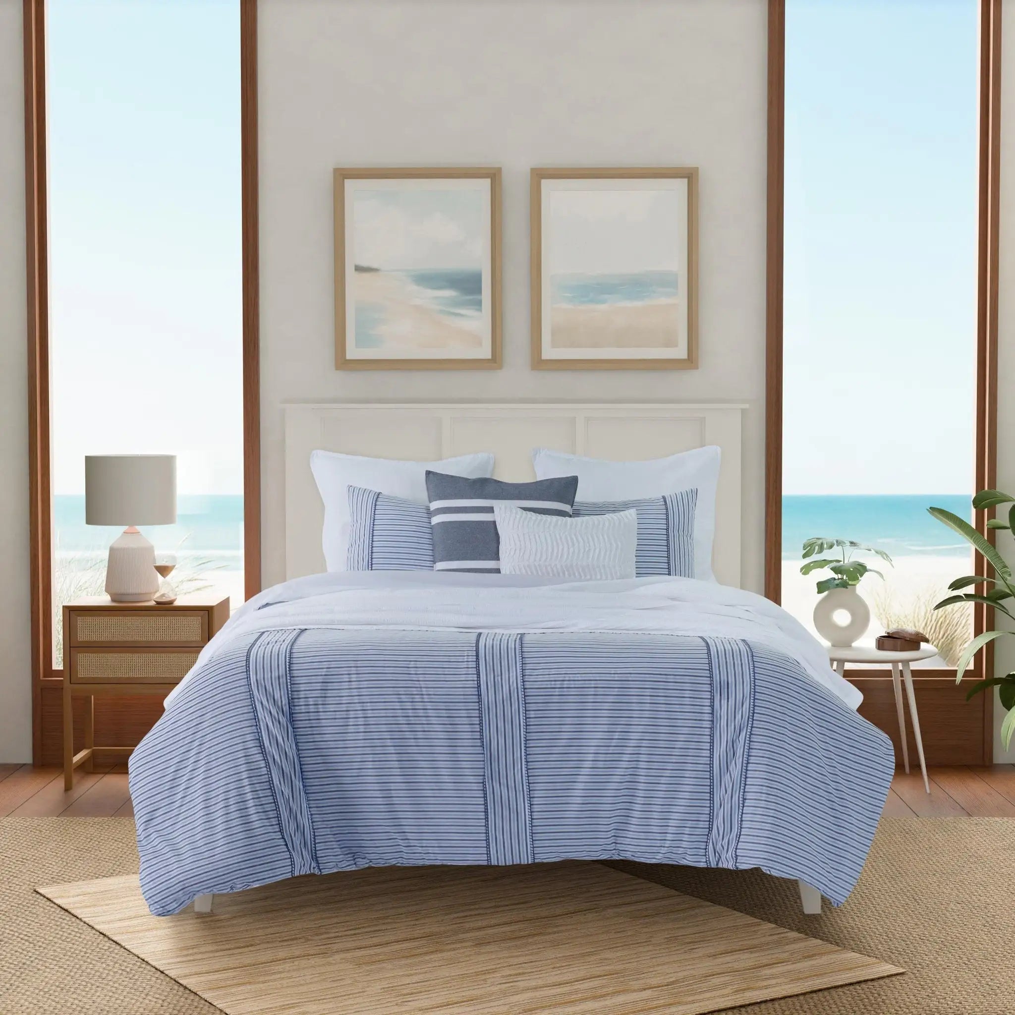 A bed dressed in a light blue and white striped bedding set with matching pillows, styled in a bright bedroom.