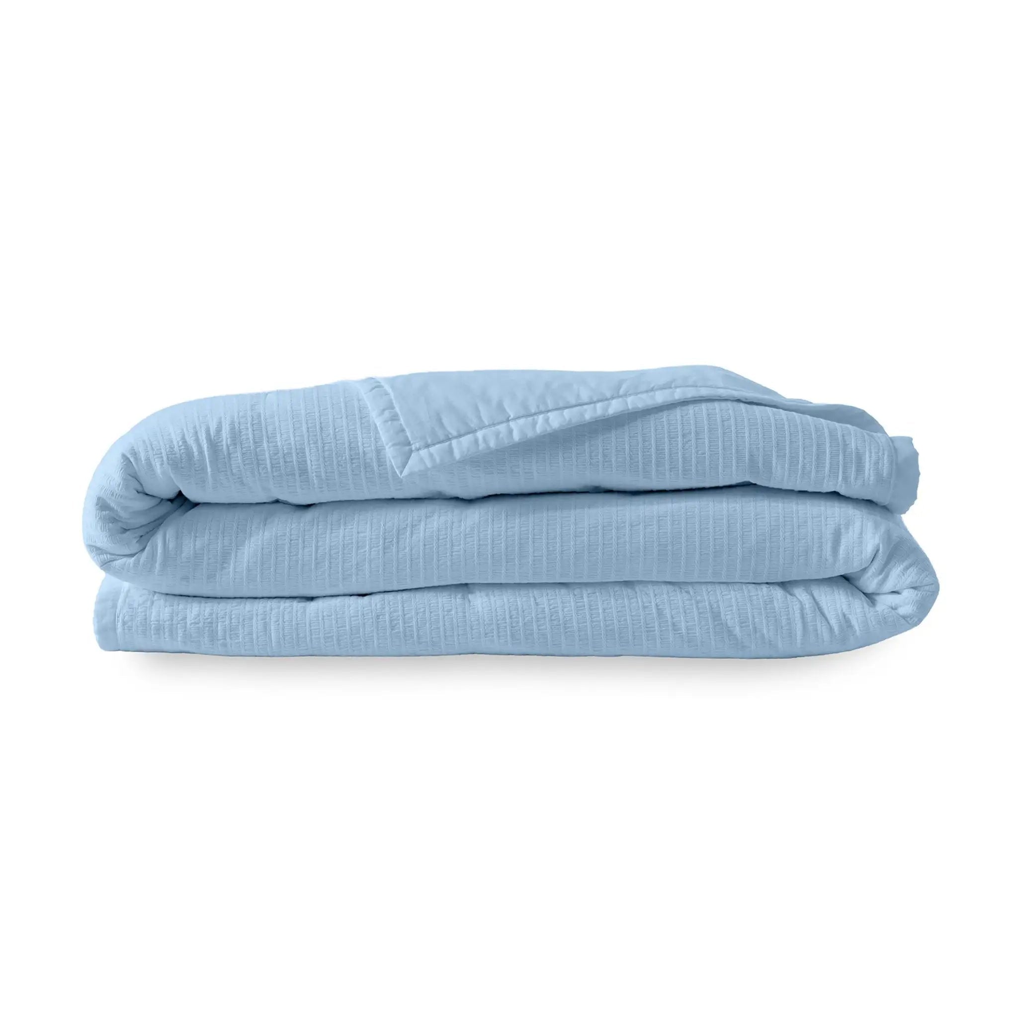 Folded light blue quilt on a white background