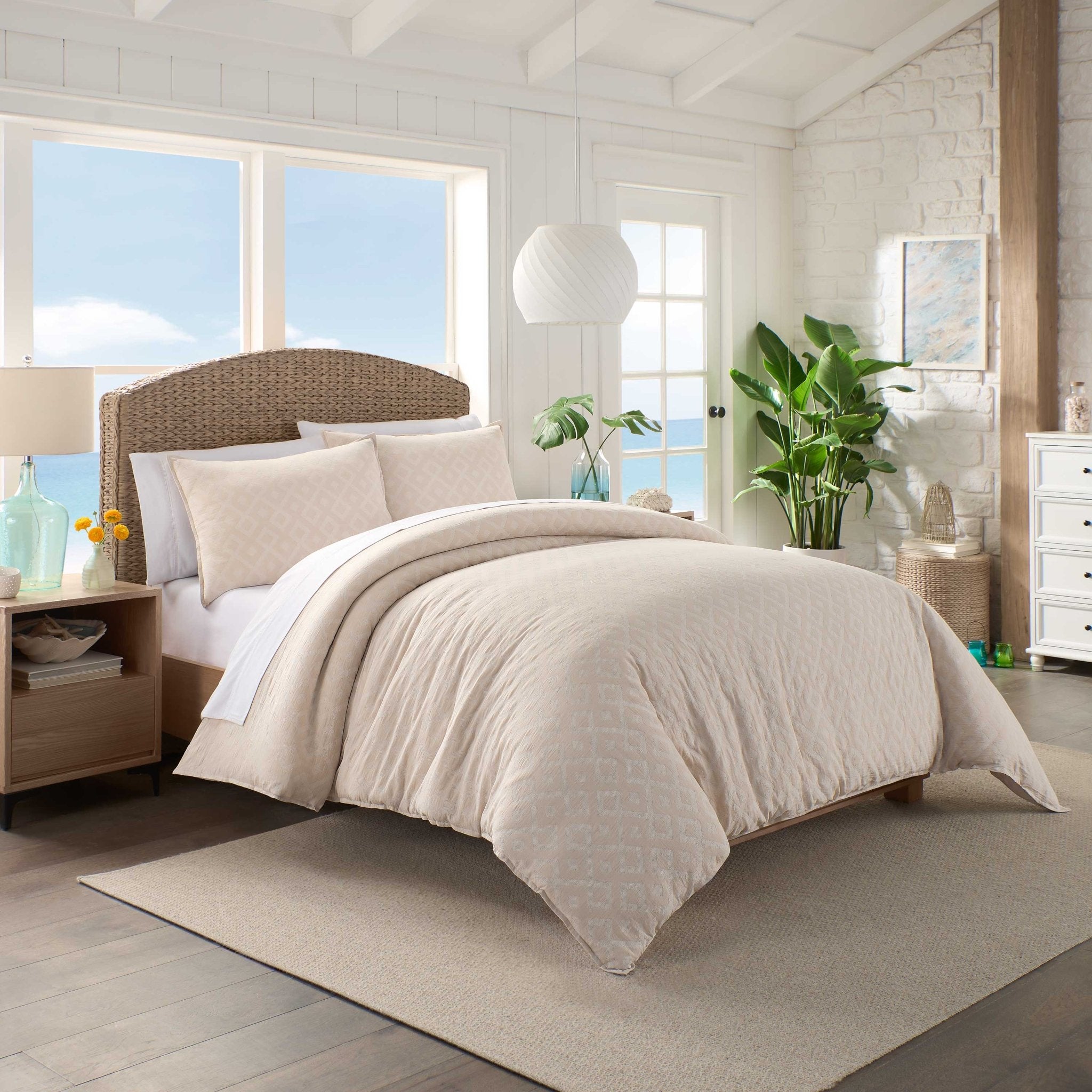 Neatly made bed with beige bedding in a bright bedroom.
