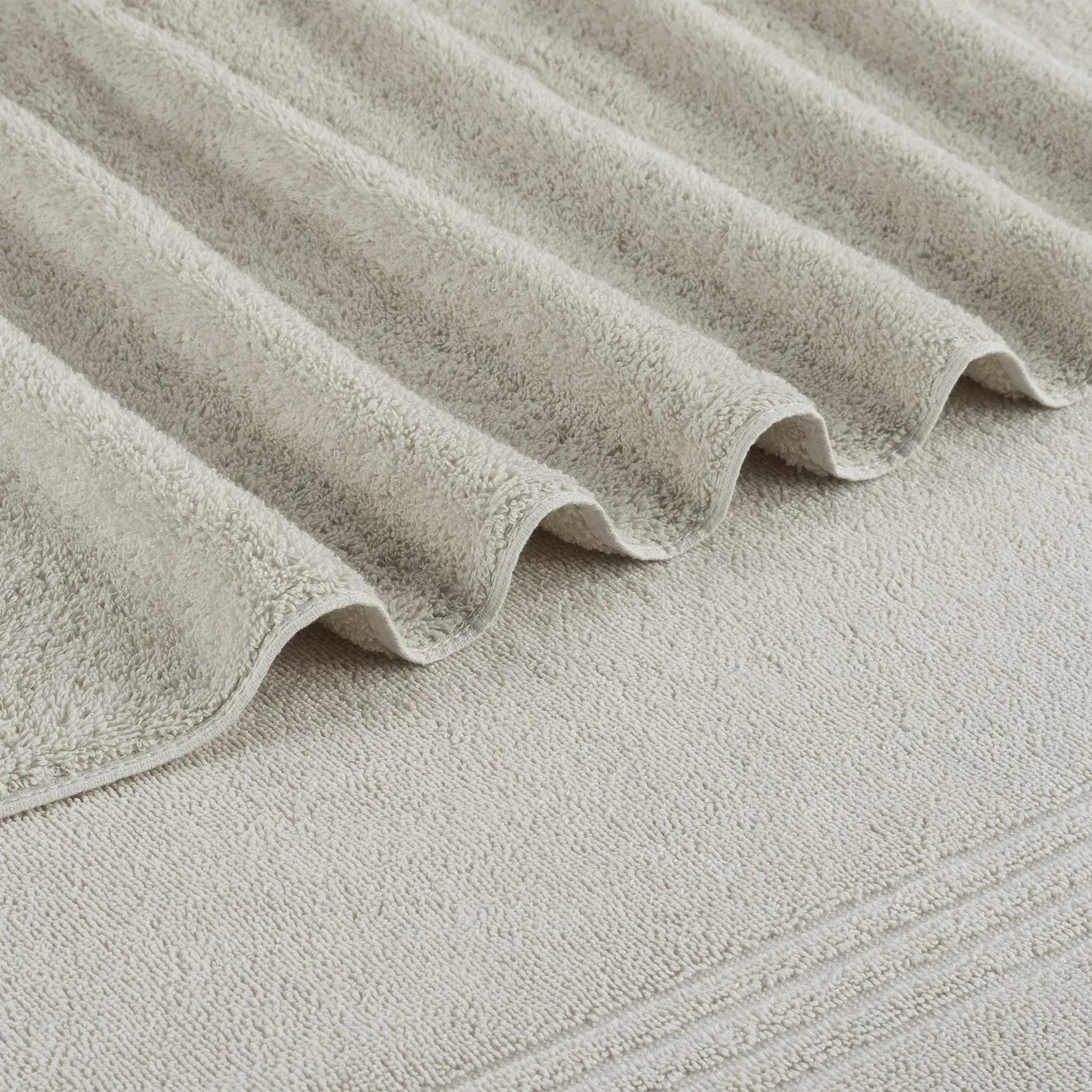 A close-up of a grey textured bath towel, showing the soft terry fabric and wavy drape.