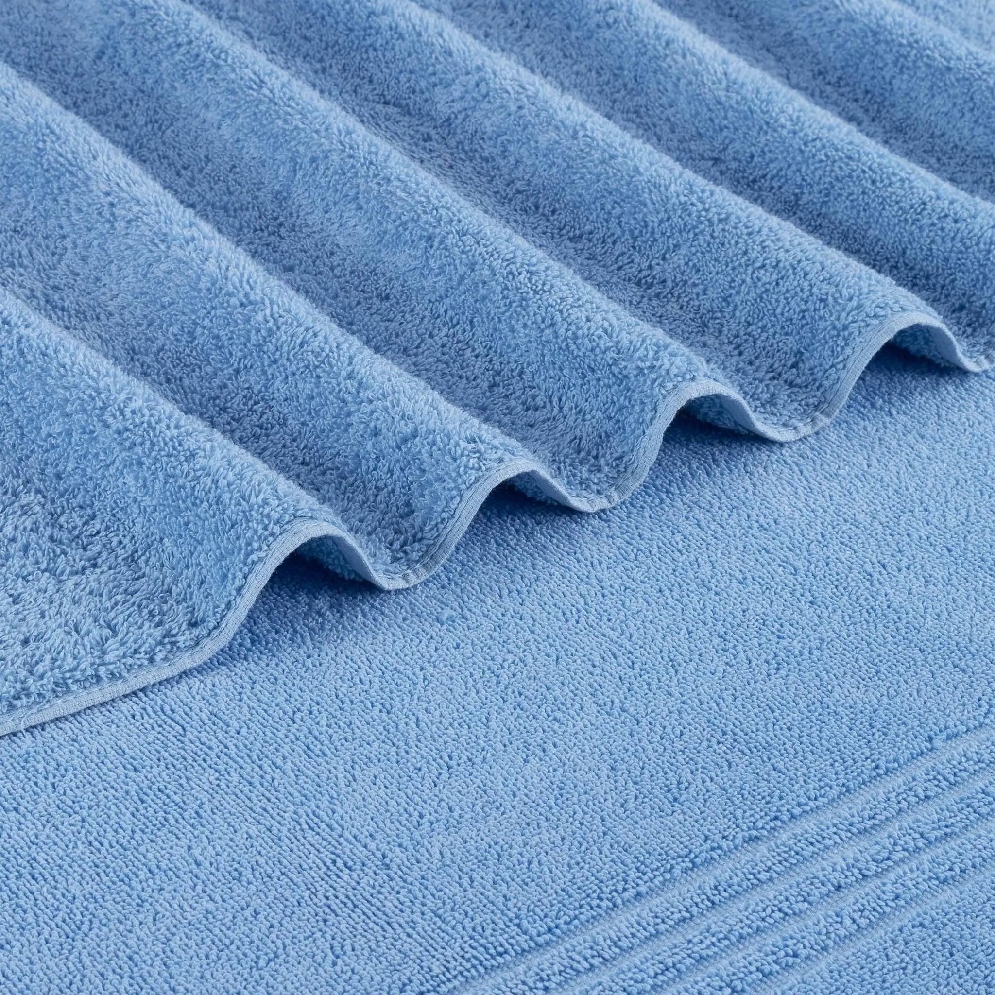 A close-up of blue bath towel with a folded corner showing the soft, textured fabric.
