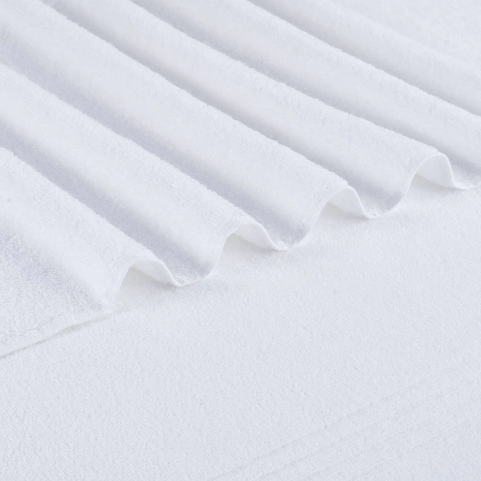 A close-up of white textured bath towel fabric with soft folds