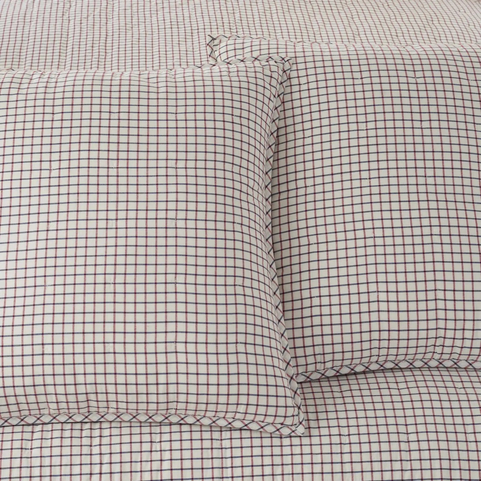 Close-up of a quilt with two matching euros in a small brown and off-white gingham check pattern.