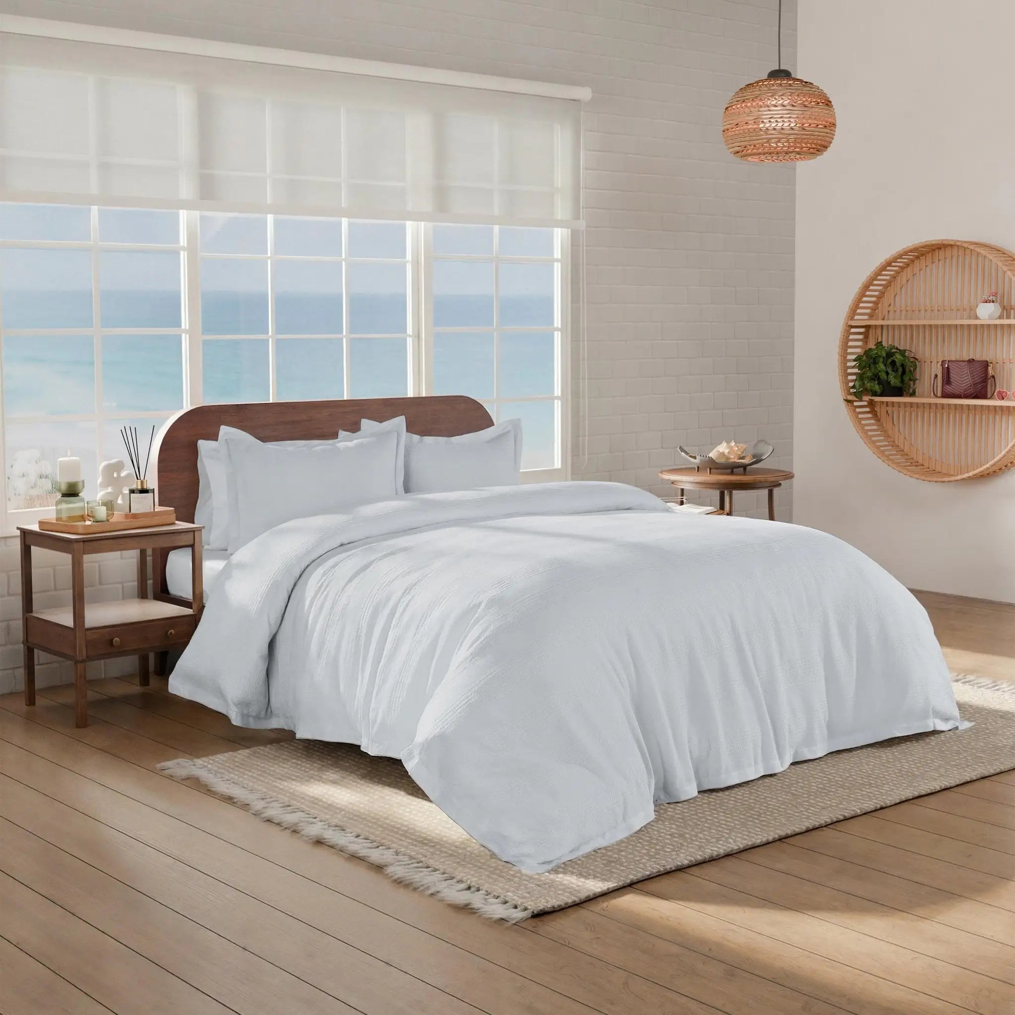 A neatly made bed with grey comforter and pillow shams in a bright, modern bedroom.