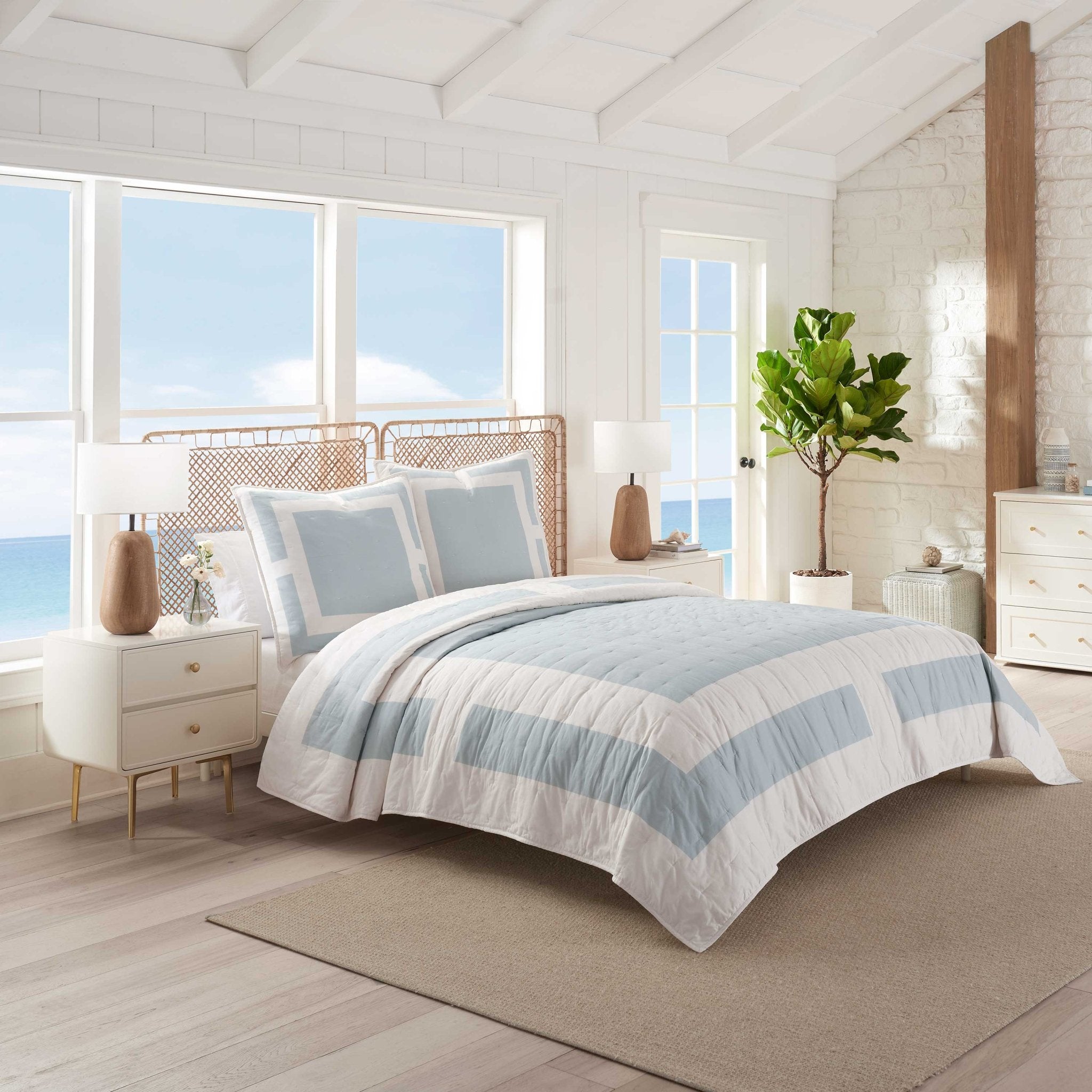 Bedroom with a bed covered in a blue and ivory striped quilt and euro.
