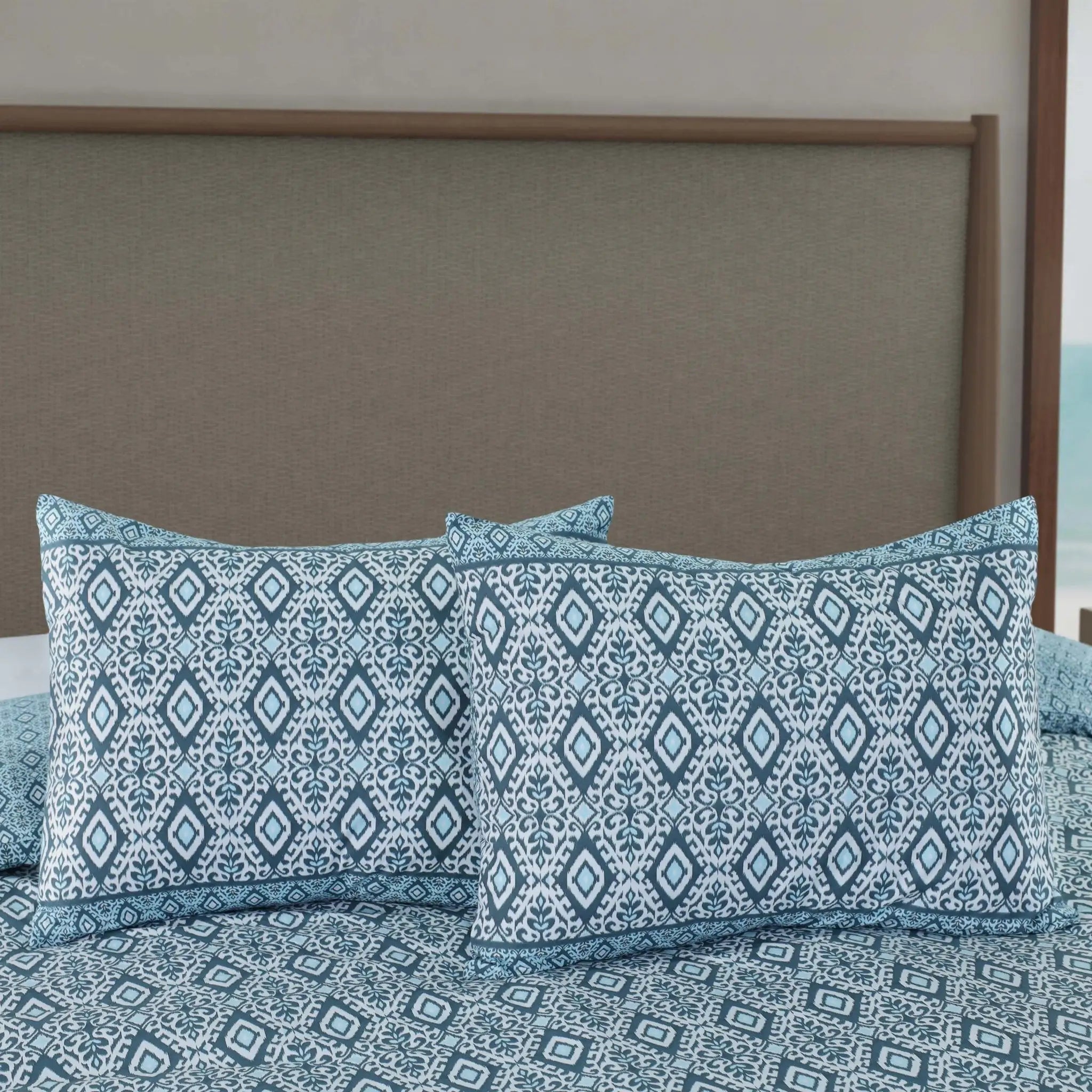 Blue patterned comforter set with two matching pillow shams displayed on a bed.