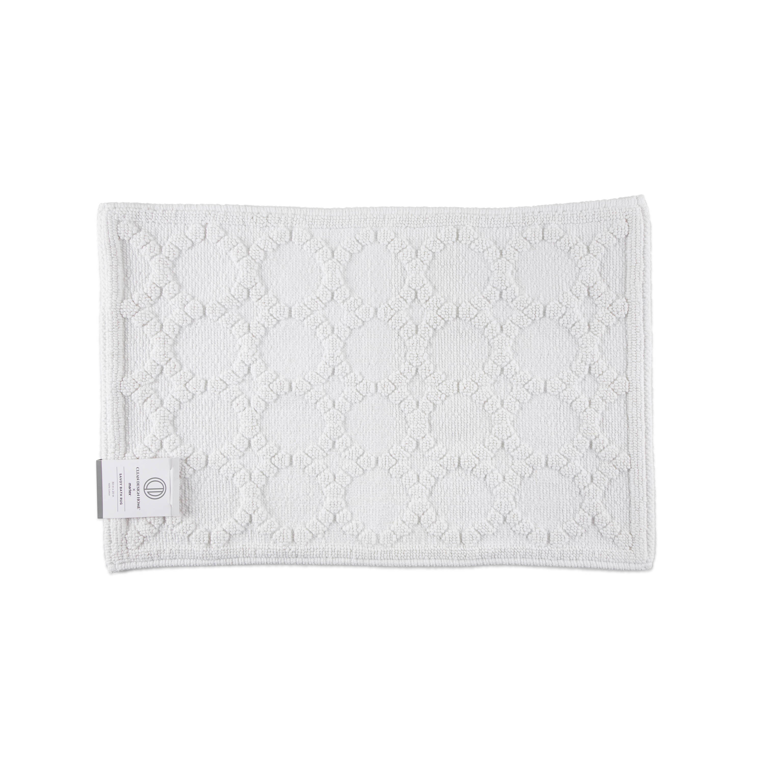 White bath rug with a textured circular pattern and a label on one corner.