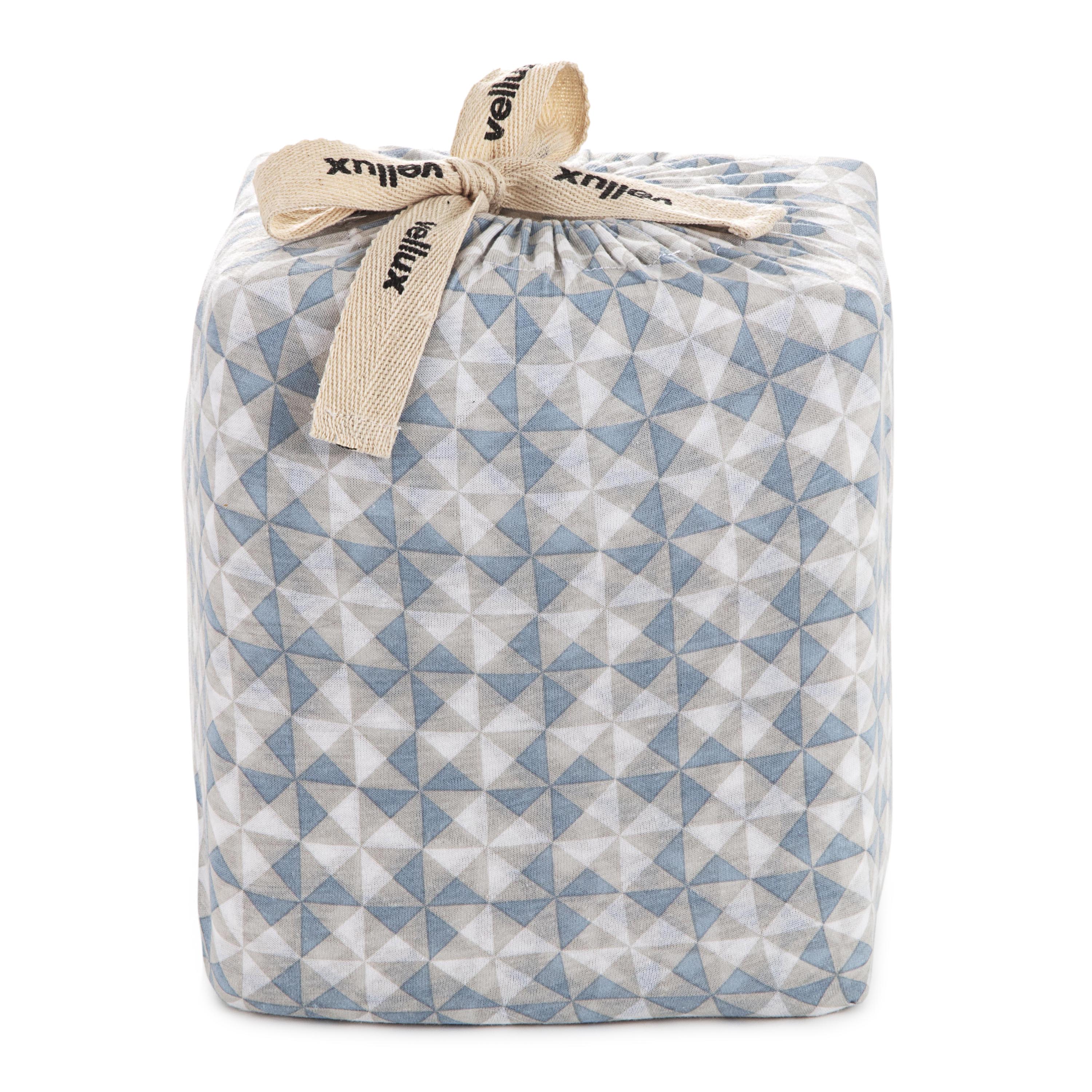 Soft blue sheet set wrapped in a geometric patterned fabric with a tied ribbon.