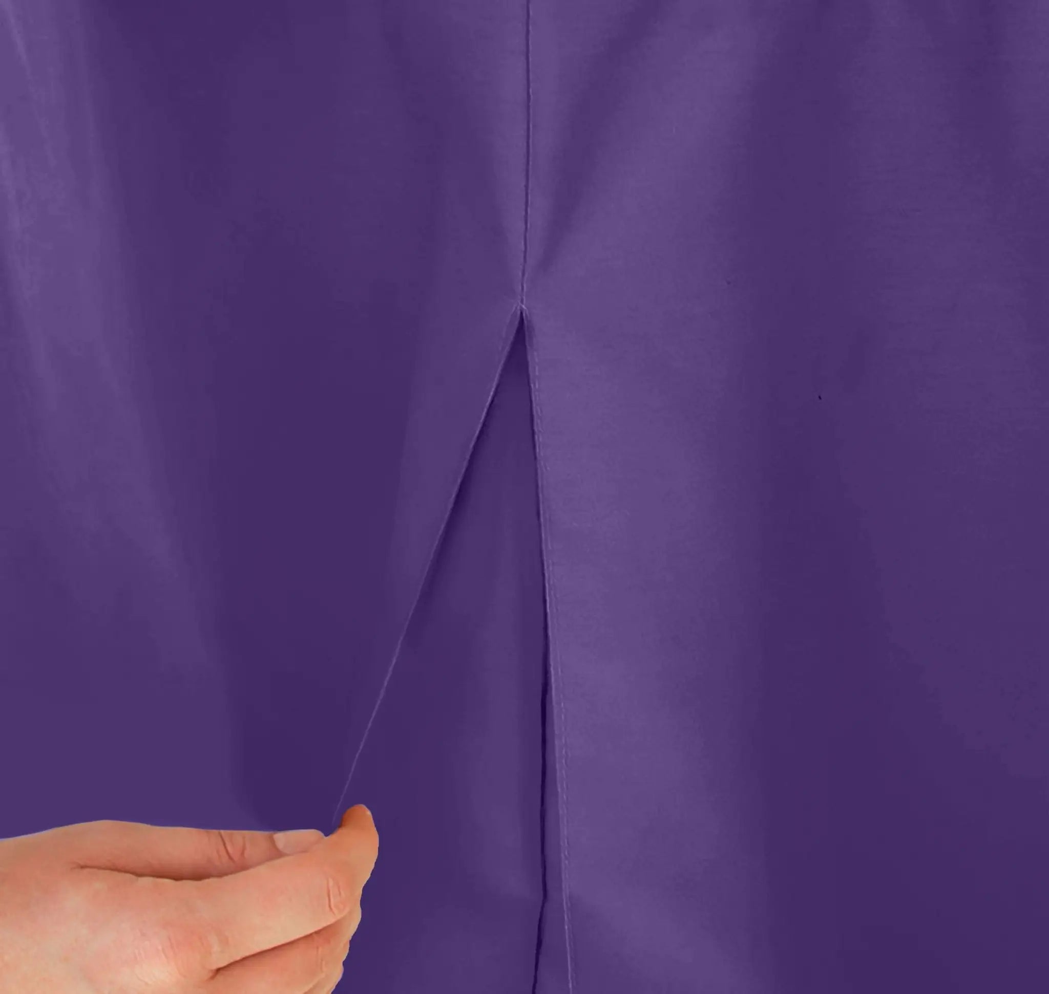 Close-up of a hand holding a violet color table cover fabric with a visible seam.