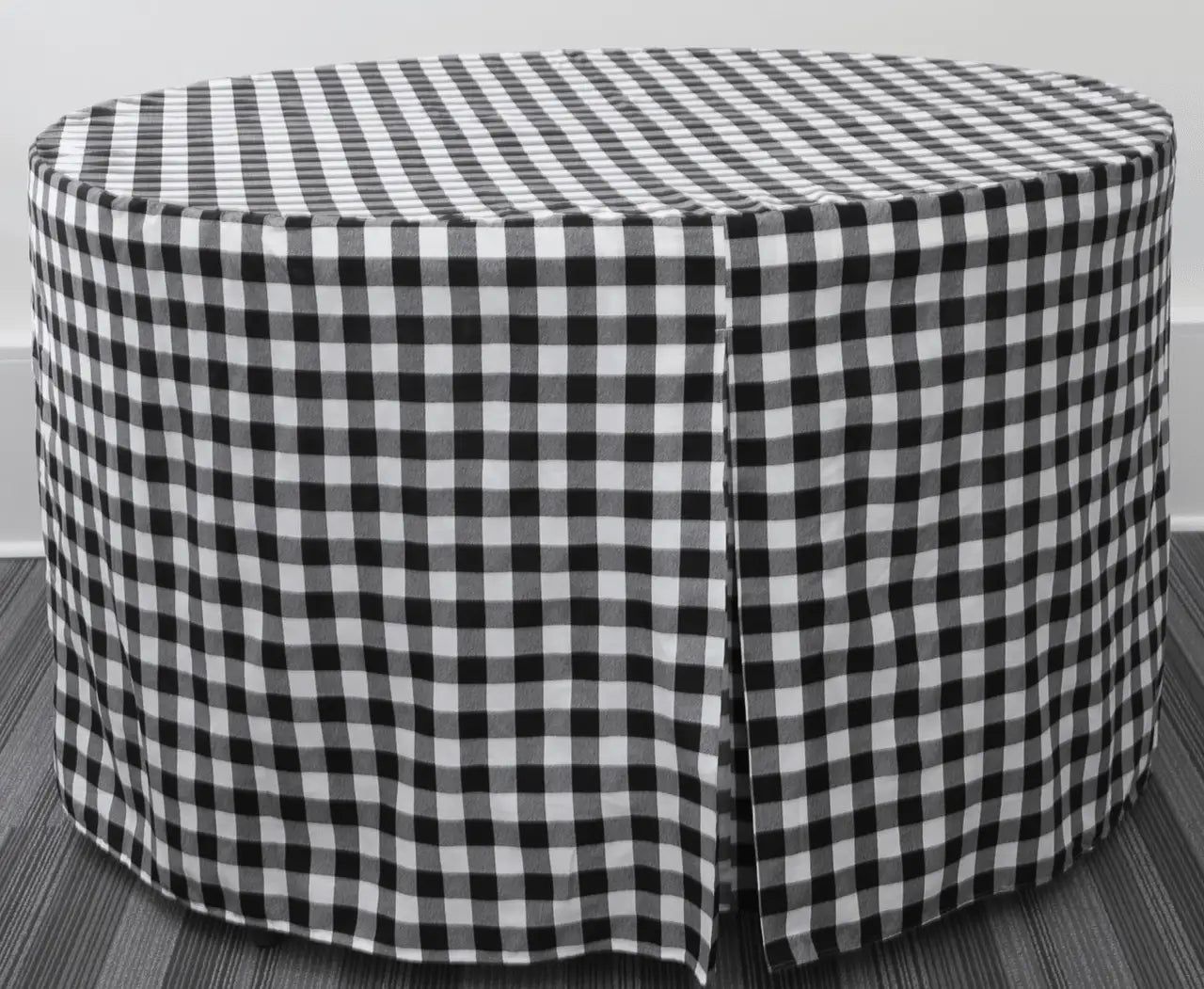 A round table covered in a black and white gingham checkered table skirt, shown against a neutral gray background.