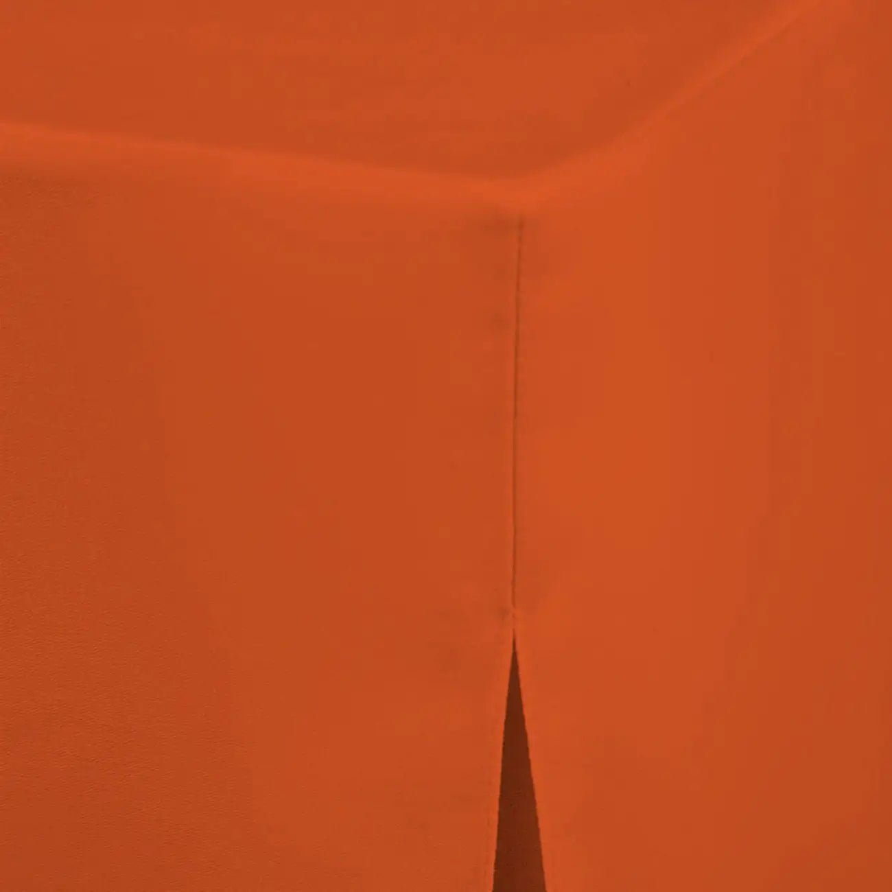 A close-up of a solid orange textured table cloth, showing a vertical seam and a pointed corner.