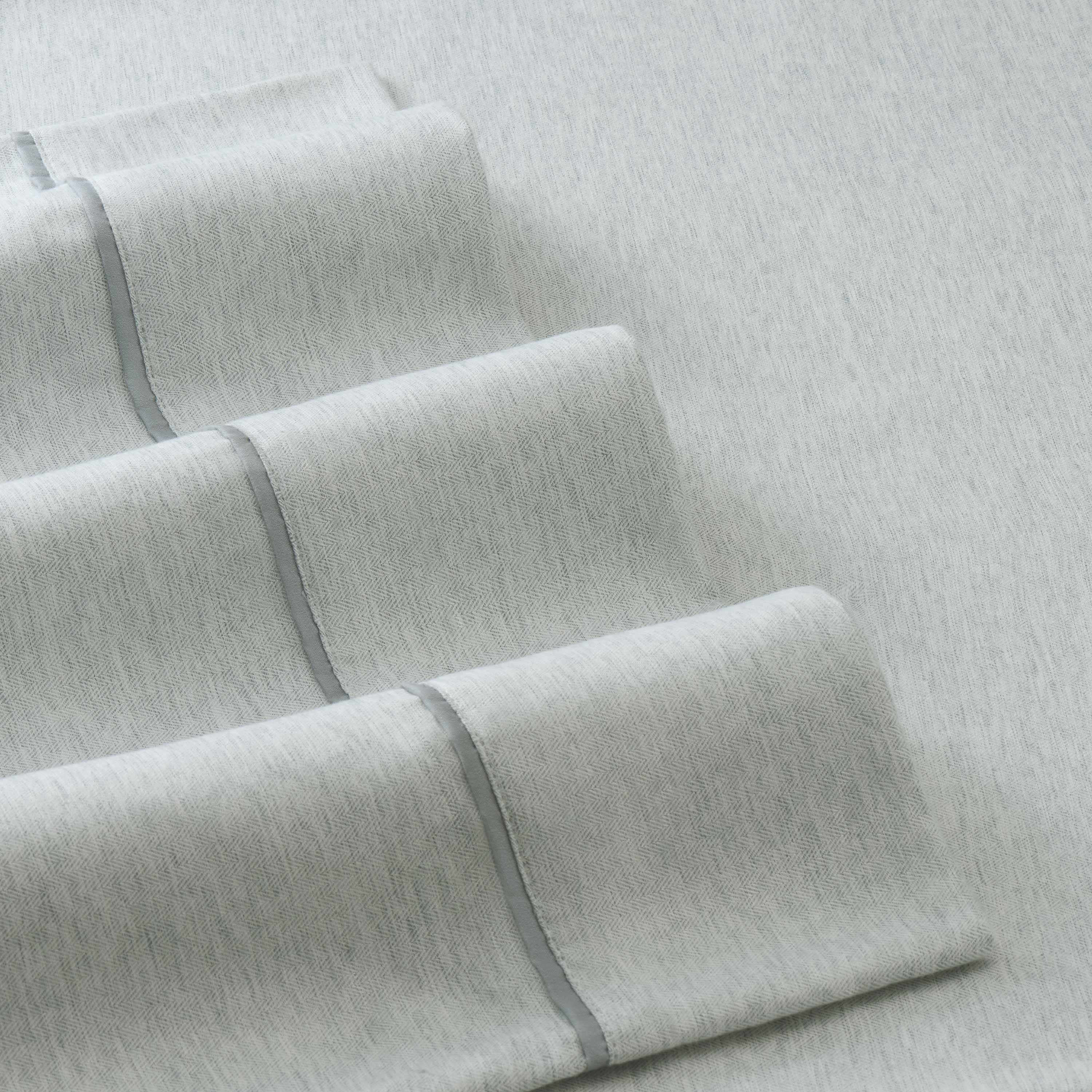Light gray herringbone patterned sheets with a smooth texture and contrasting trim.