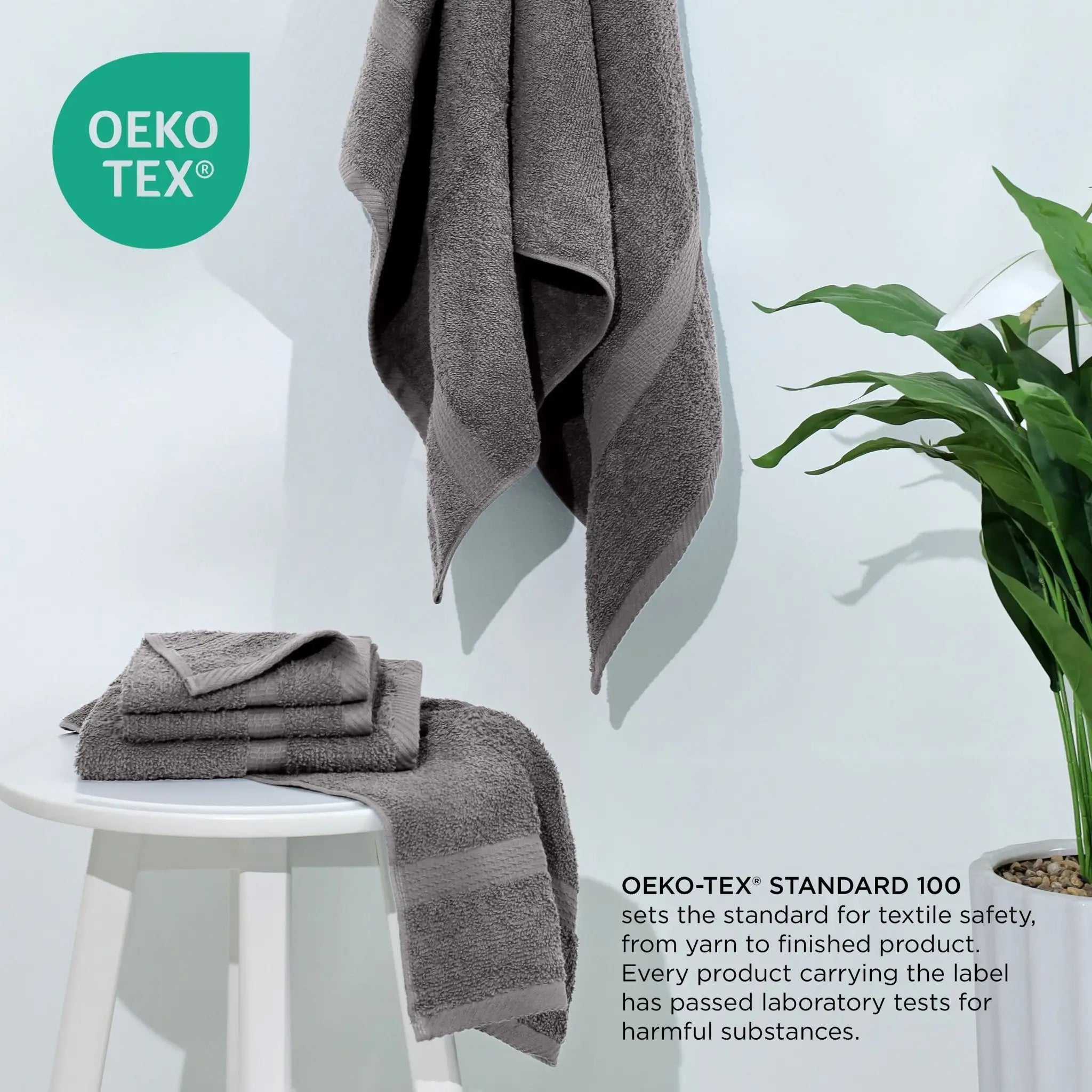 Gray towels on a white stool with a plant, featuring the Oeko-Tex logo.