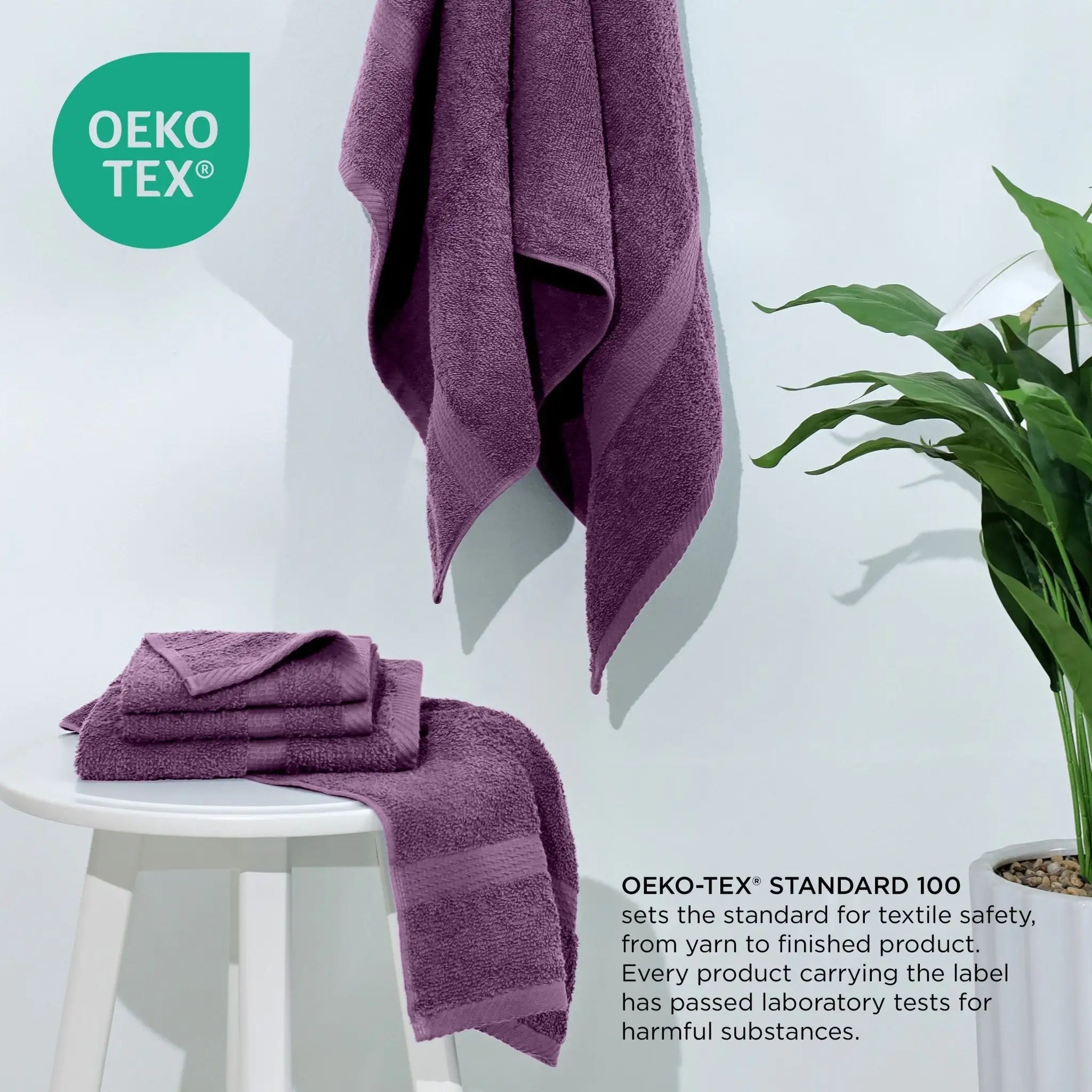 Purple towels on a white stool with a plant, featuring the Oeko-Tex logo.