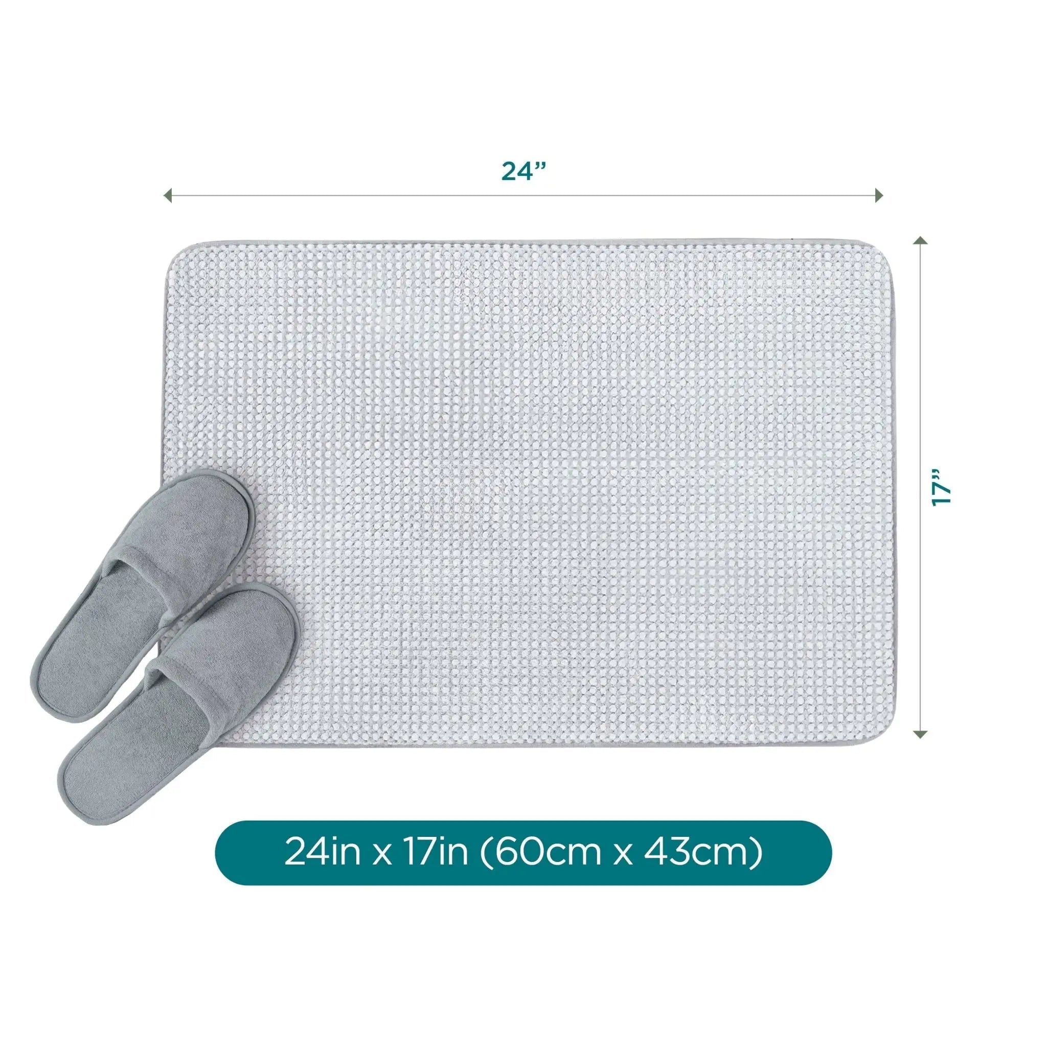 A rectangular light gray bath rug with rounded corners shown on a white background, with dimension arrows indicating 24 inches by 17 inches. A pair of gray slippers rests on the lower left, and a teal label at the bottom reads 24in x 17in (60cm x 43cm).
