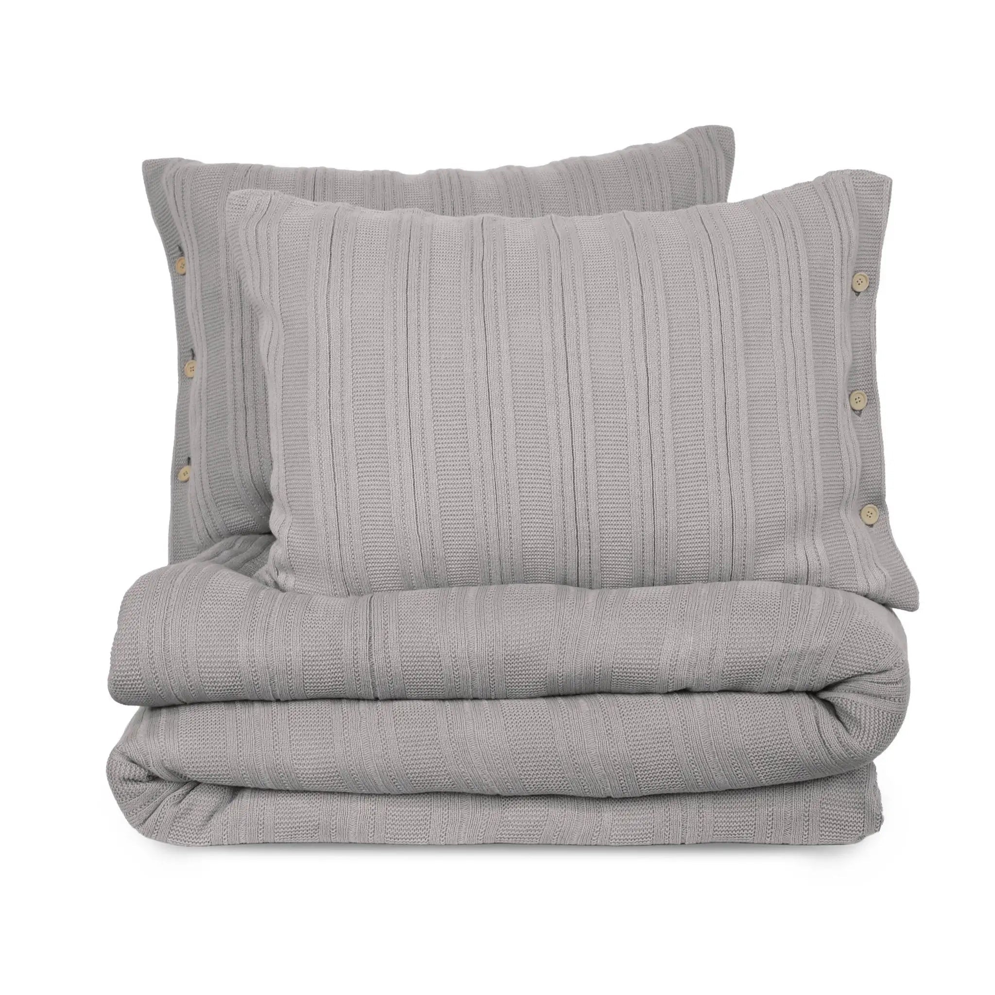 Folded gray textured blanket with two matching pillows on a white background