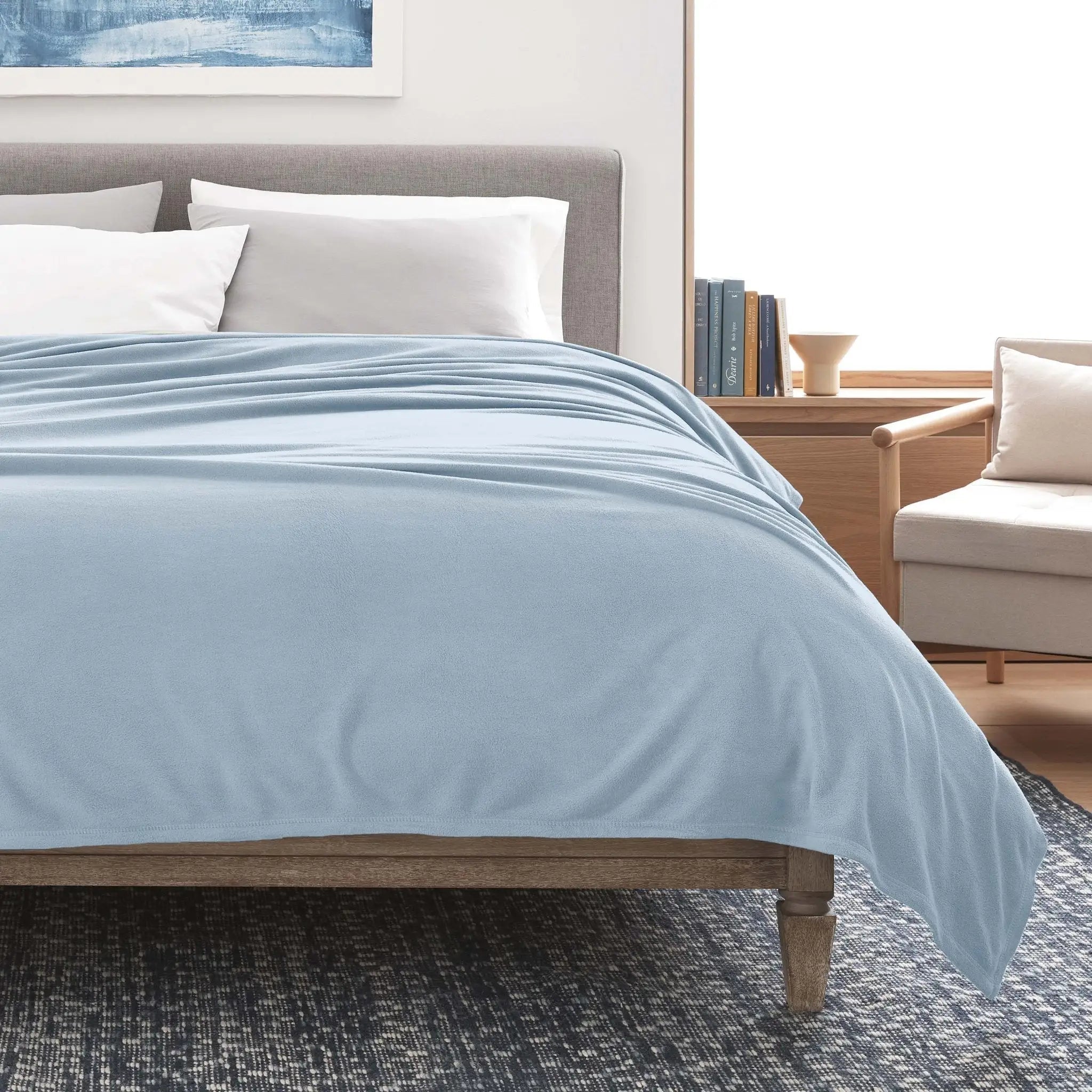 Bed with light blue blanket in a bedroom setting
