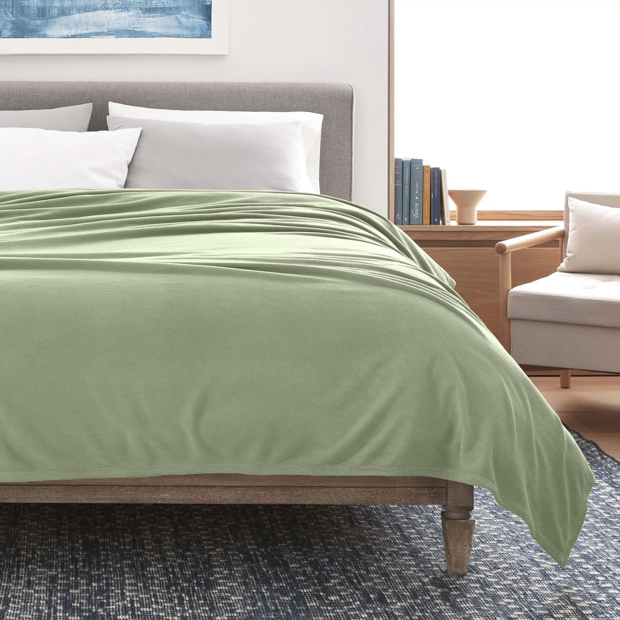 A sage blanket over a bed in a modern bedroom setting.