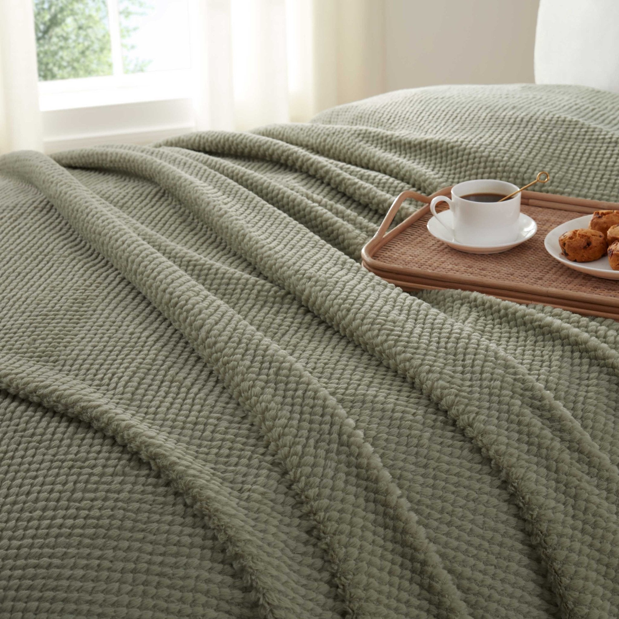 Green blanket draped over a bed
