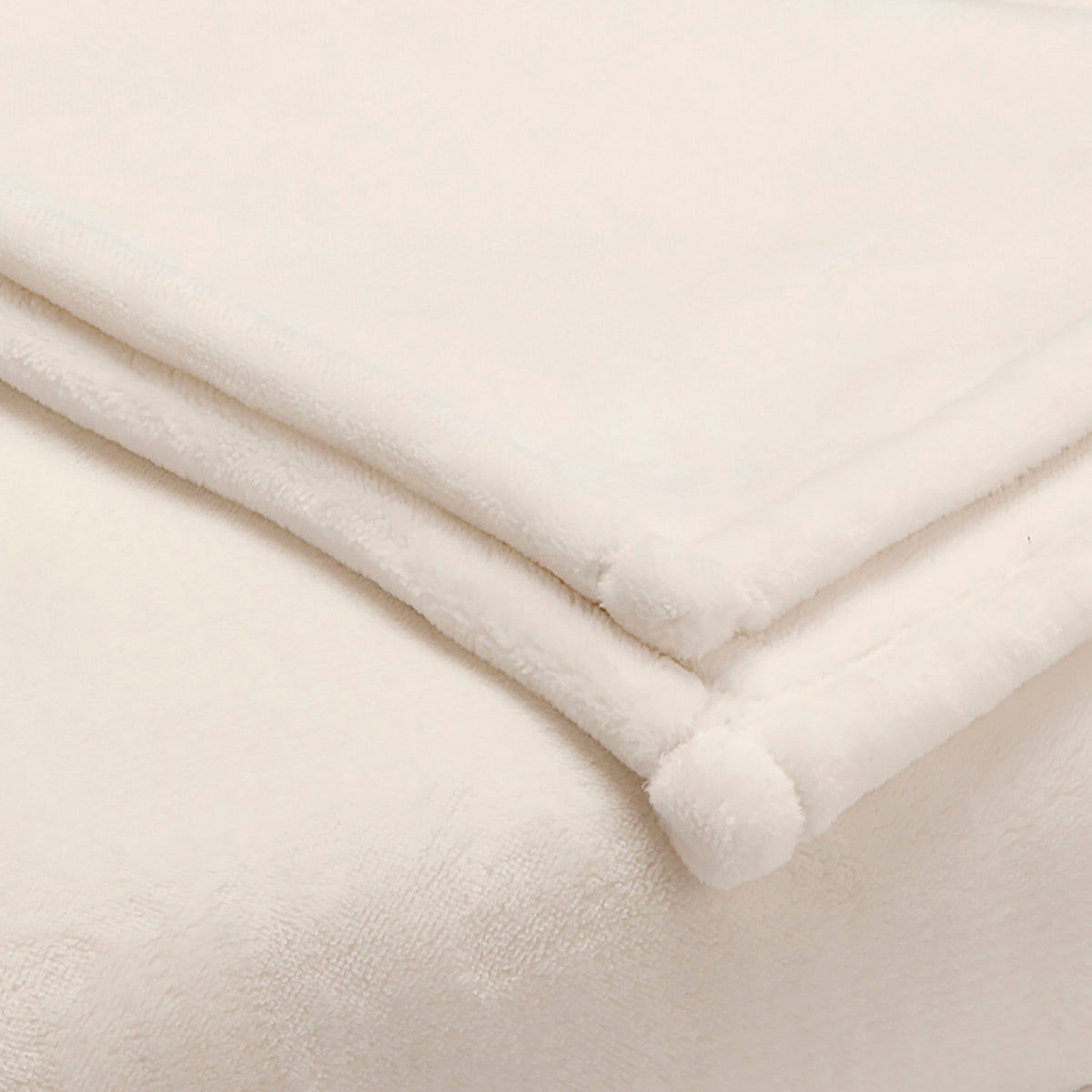 Soft, sheared faux mink blanket in a light cream color, folded with rounded corners.