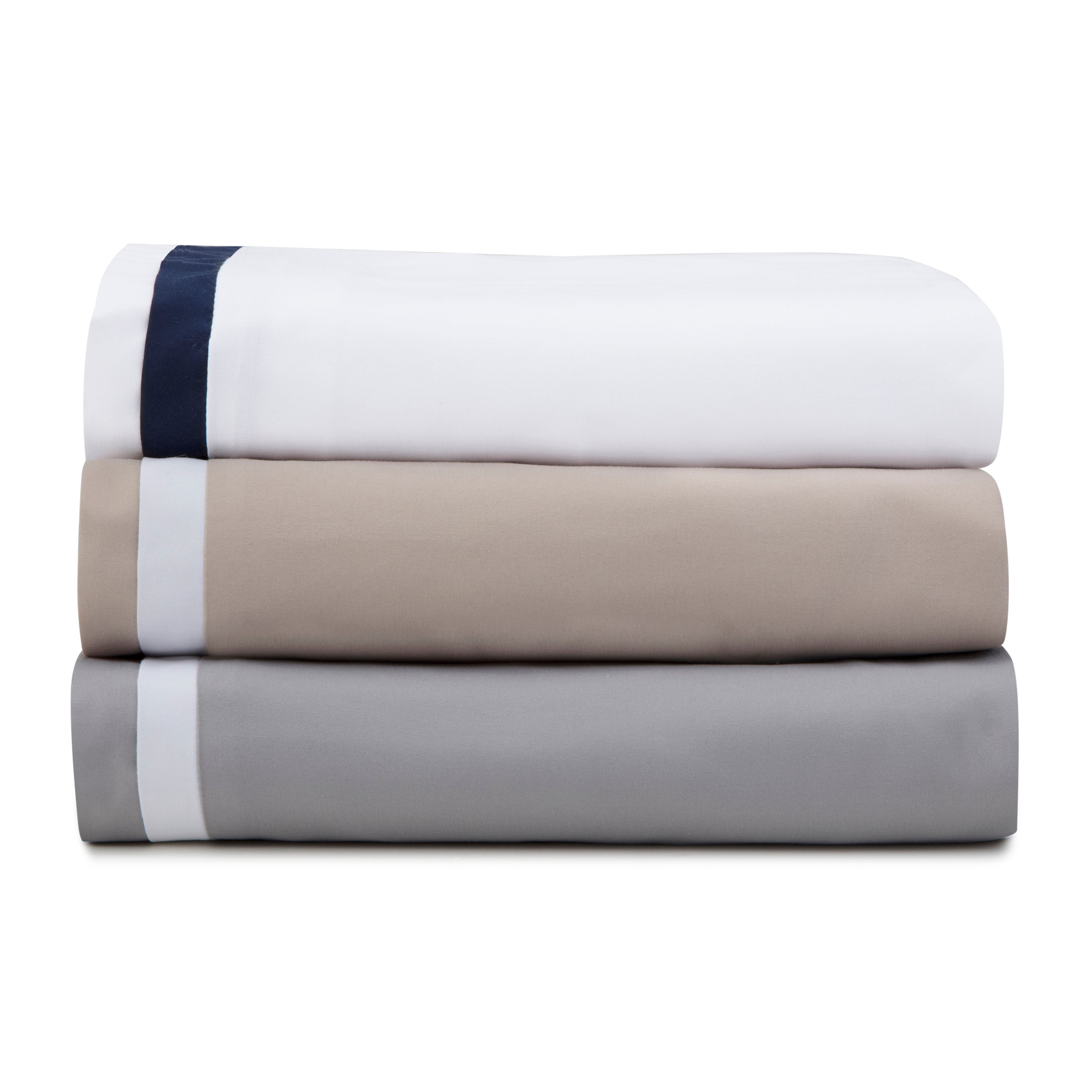 Three stacked duvet covers in white, beige, and gray, featuring contrasting trim at the top.
