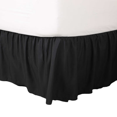 Black ruffle bed skirt drapes around the base of a bed, covering the box spring and floor beneath.