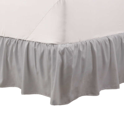 Gray ruffle bed skirt drapes elegantly along the bottom of a bed, covering the box spring.