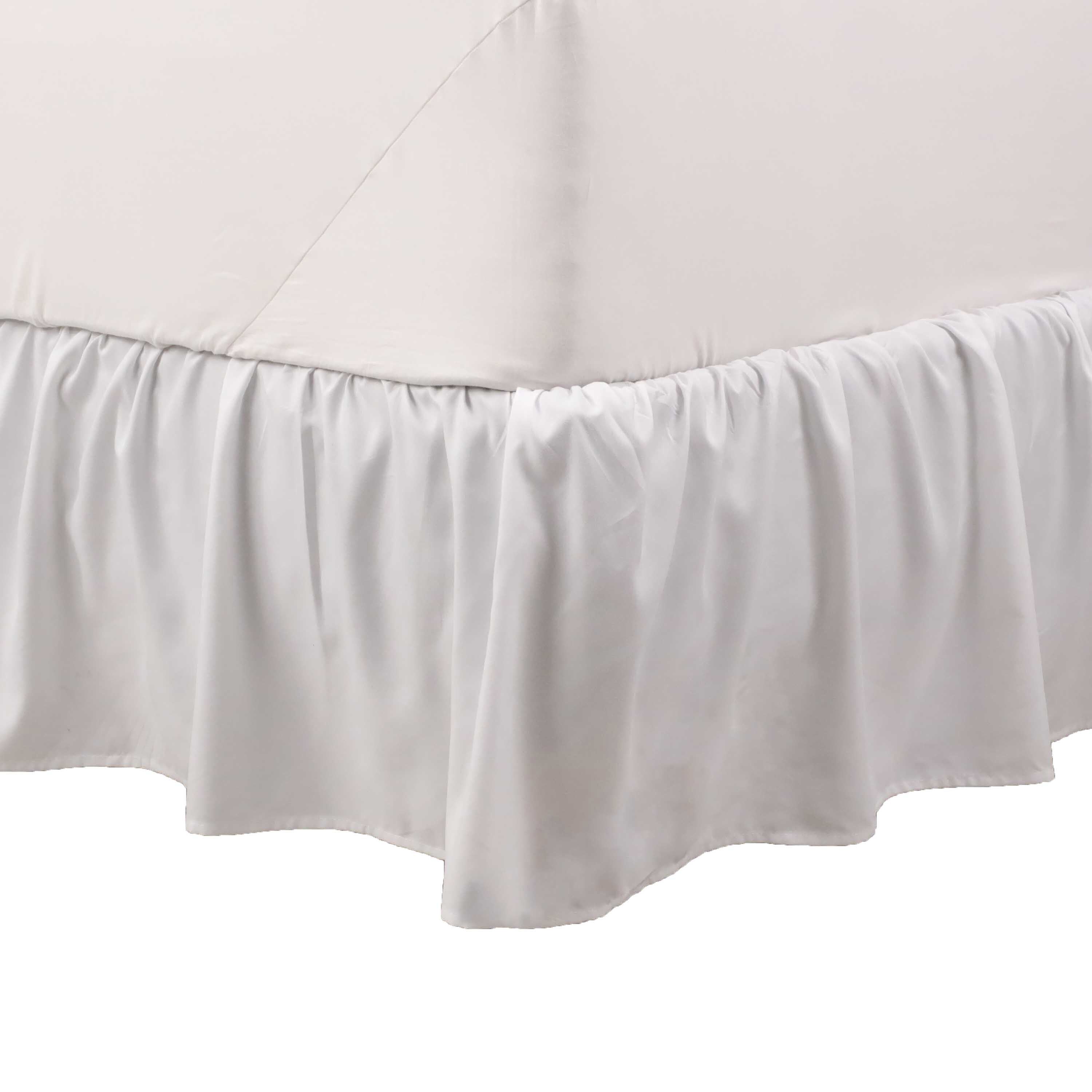 White ruffle bed skirt draping from the edge of a bed, covering the box spring.