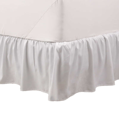 White ruffle bed skirt draping from the edge of a bed, covering the box spring.