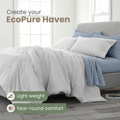 Light gray comforter set on a bed with blue and white pillows, featuring a light and airy design.