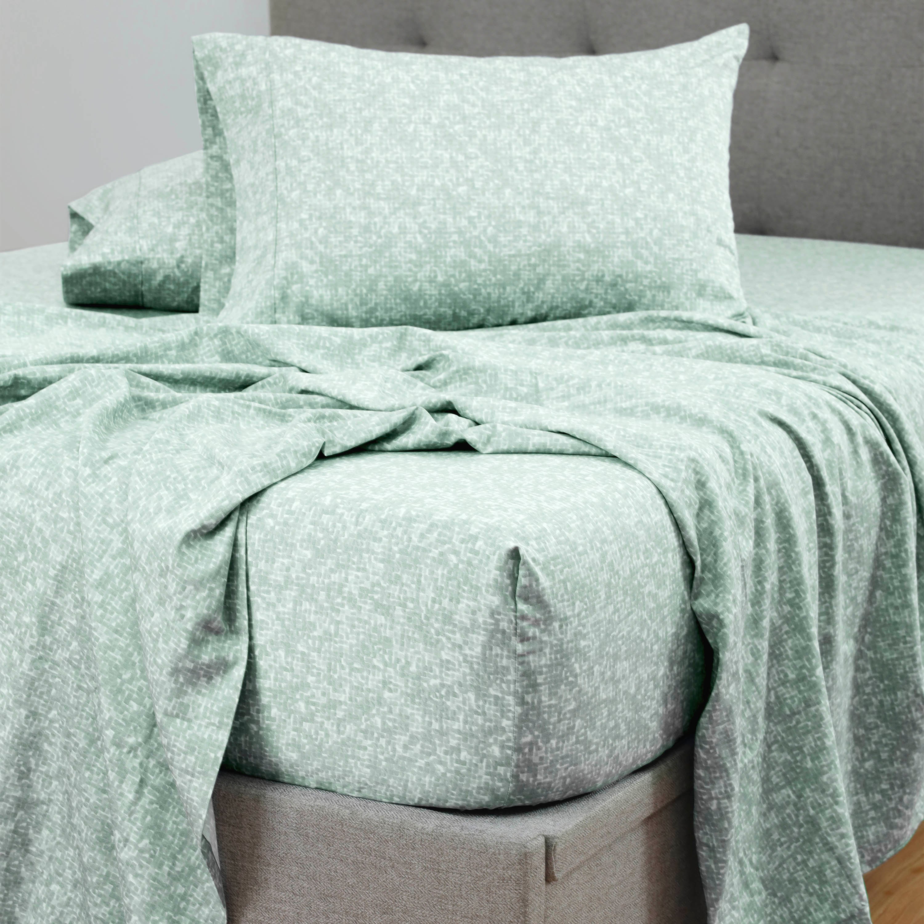 Green patterned sheet set laid out on a bed with matching pillowcases.